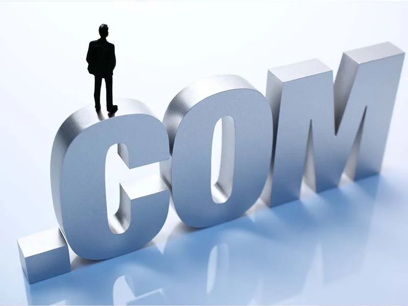 Person standing on large .COM letters, representing an online business presence