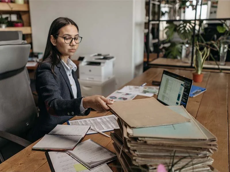 Employee reviewing business records and reports at a desk to prepare for seasonal demand fluctuations.