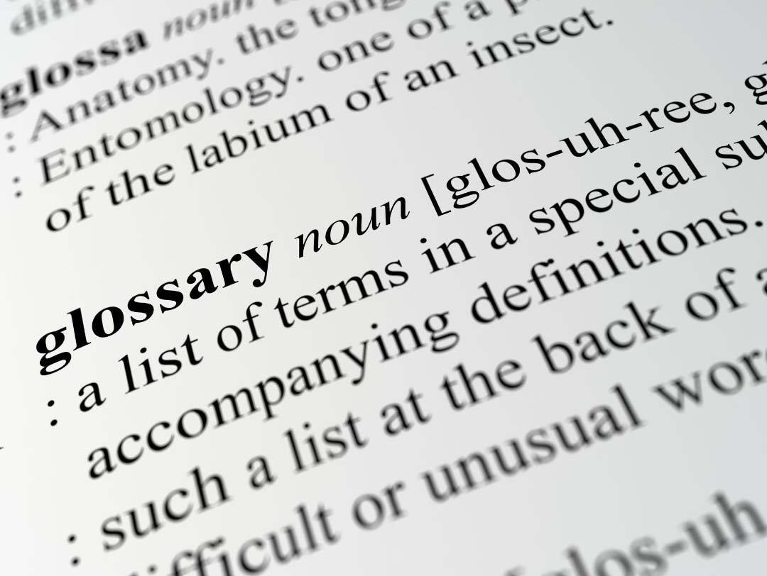 Close-up of a printed dictionary page showing the bolded definition of the word “glossary” with phonetic spelling and explanatory text.