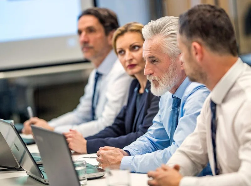 Executive team meeting in a conference room discussing business strategy and organizational planning.