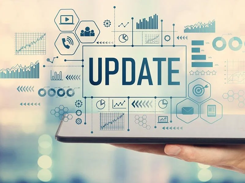 Digital tablet showing an “Update” message surrounded by analytics charts, graphs, and business performance icons.
