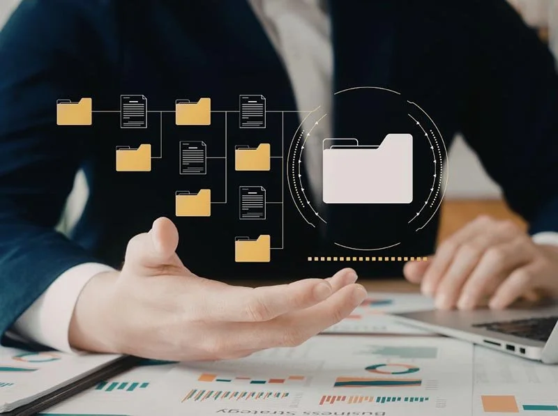 Business professional presenting a digital file management system with connected folders and documents over financial reports.