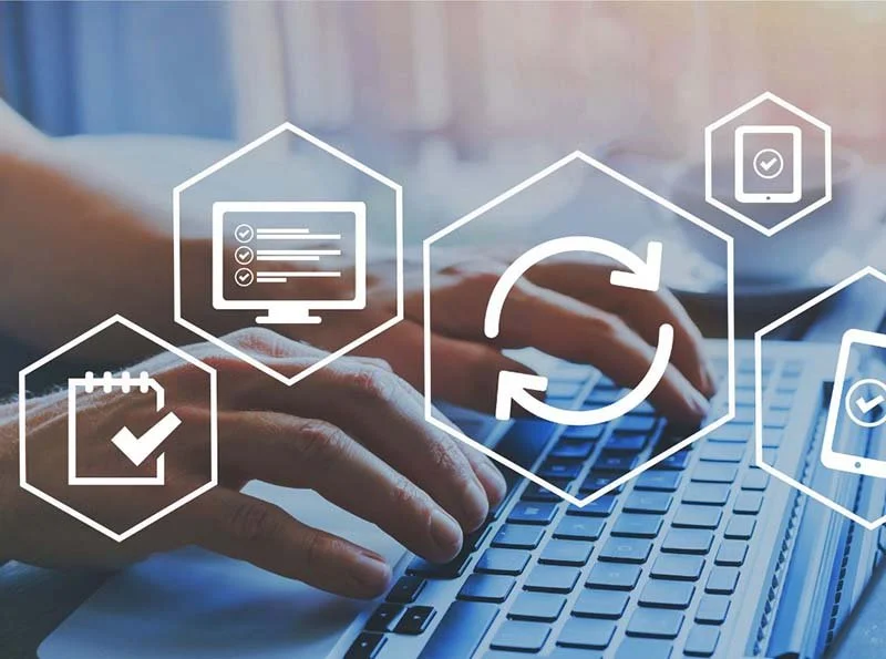 Hands typing on a laptop keyboard with digital icons representing task management, software updates, data synchronization, and mobile device security.