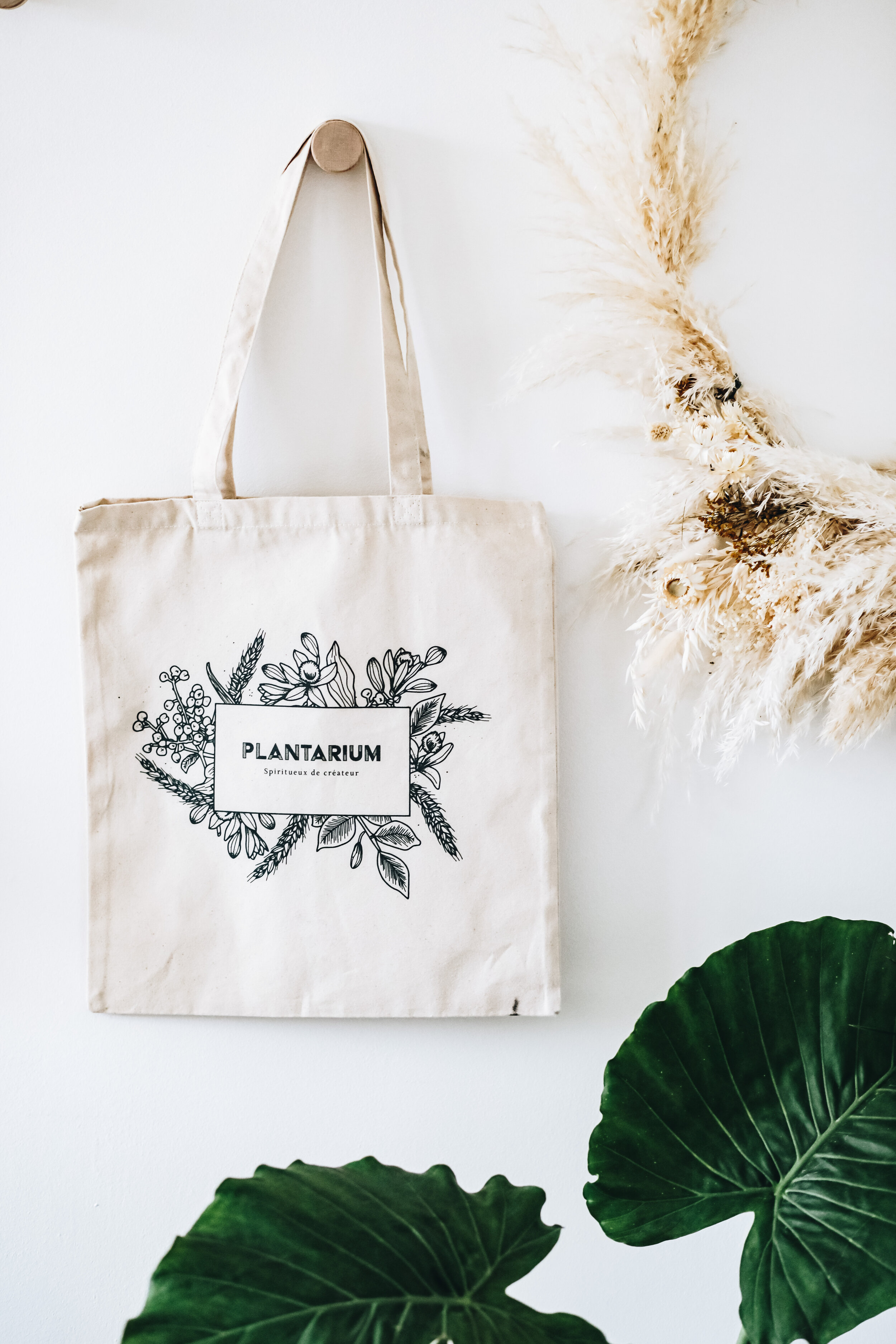 Tote bag en coton bio suspendu au mure par un arc-boutant vue de face.