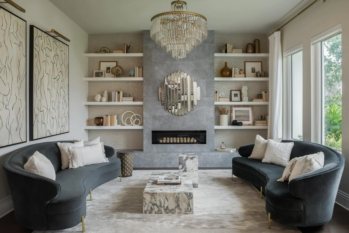 We created this custom sitting room in a way that curates a collected, modern look for our client to enjoy a glass of wine with friends. They loved a little sparkle so we infused that crystal chandelier with sleek curved mirroring sofas. Every detail