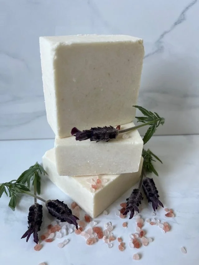 Stack of three bars of sea salt soap with lavender sprigs and pink Himalayan salt crystals around them.