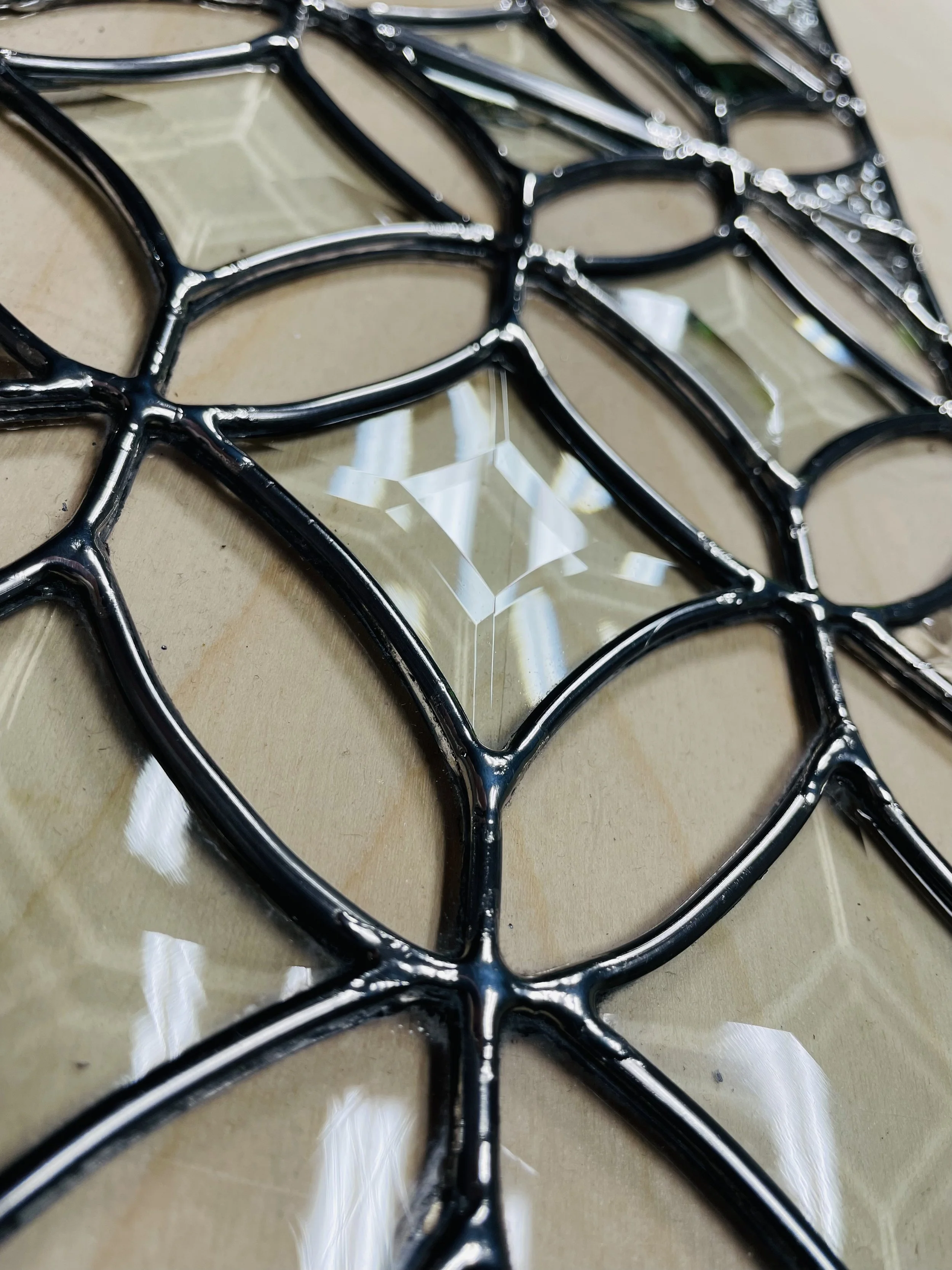 Decorative wall mirror with a black metal geometric frame and a central square mirror.