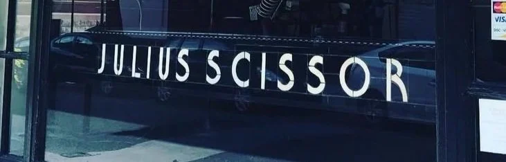 Storefront window with the name 'JULIUS SCISSOR' in large white letters.