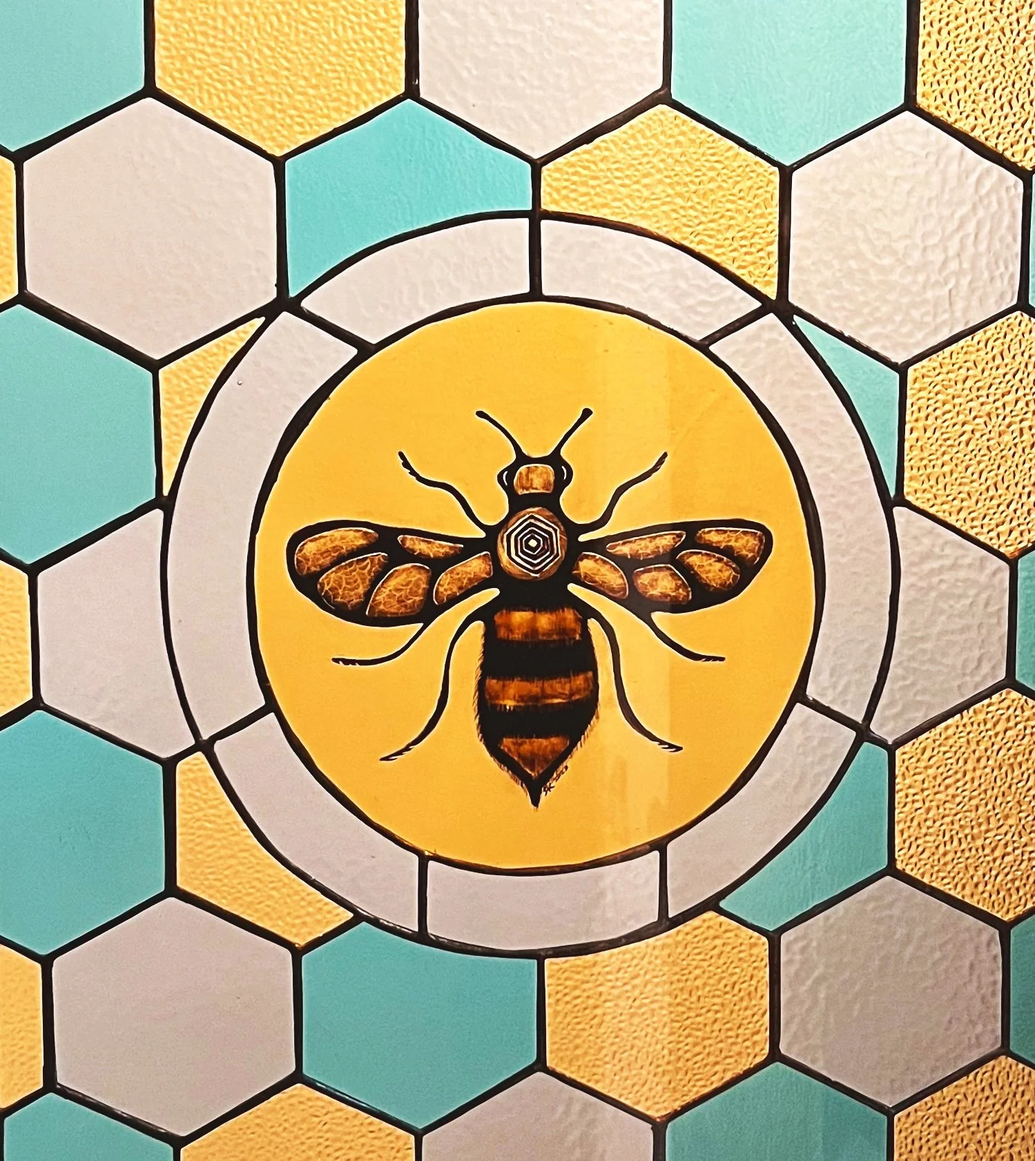Decorative sticker of a bee on a yellow circle, surrounded by a honeycomb pattern of hexagons in shades of yellow, grey, and teal.