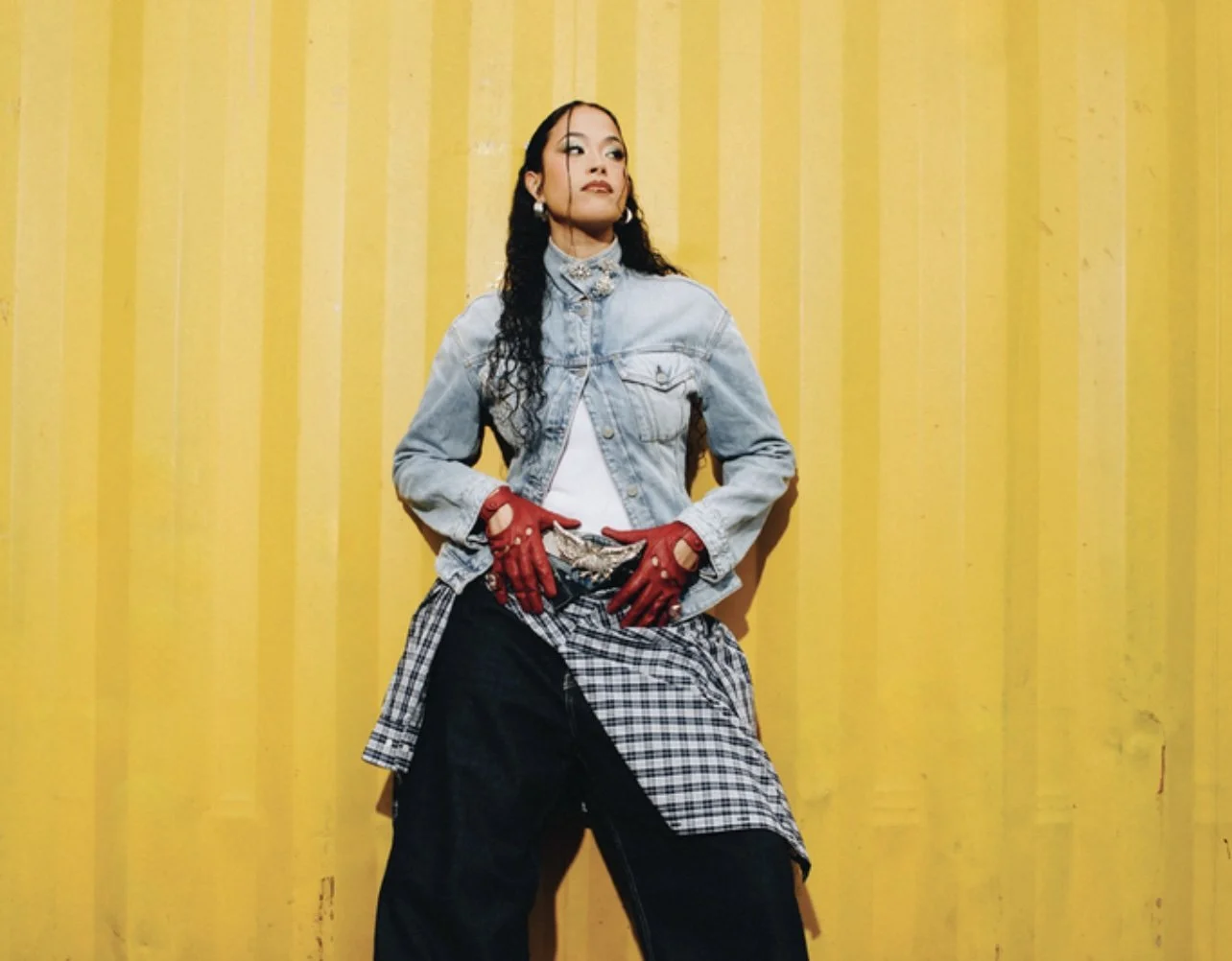 Jazzy, posing in front of a yellow corrugated metal backdrop.
