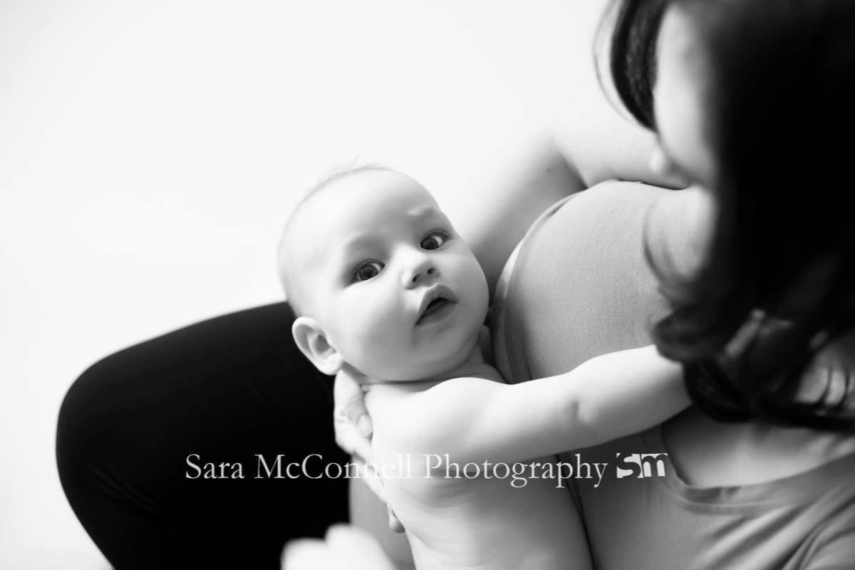 Infant who was breastfeeding looking up at the camera as the picture is being taken.