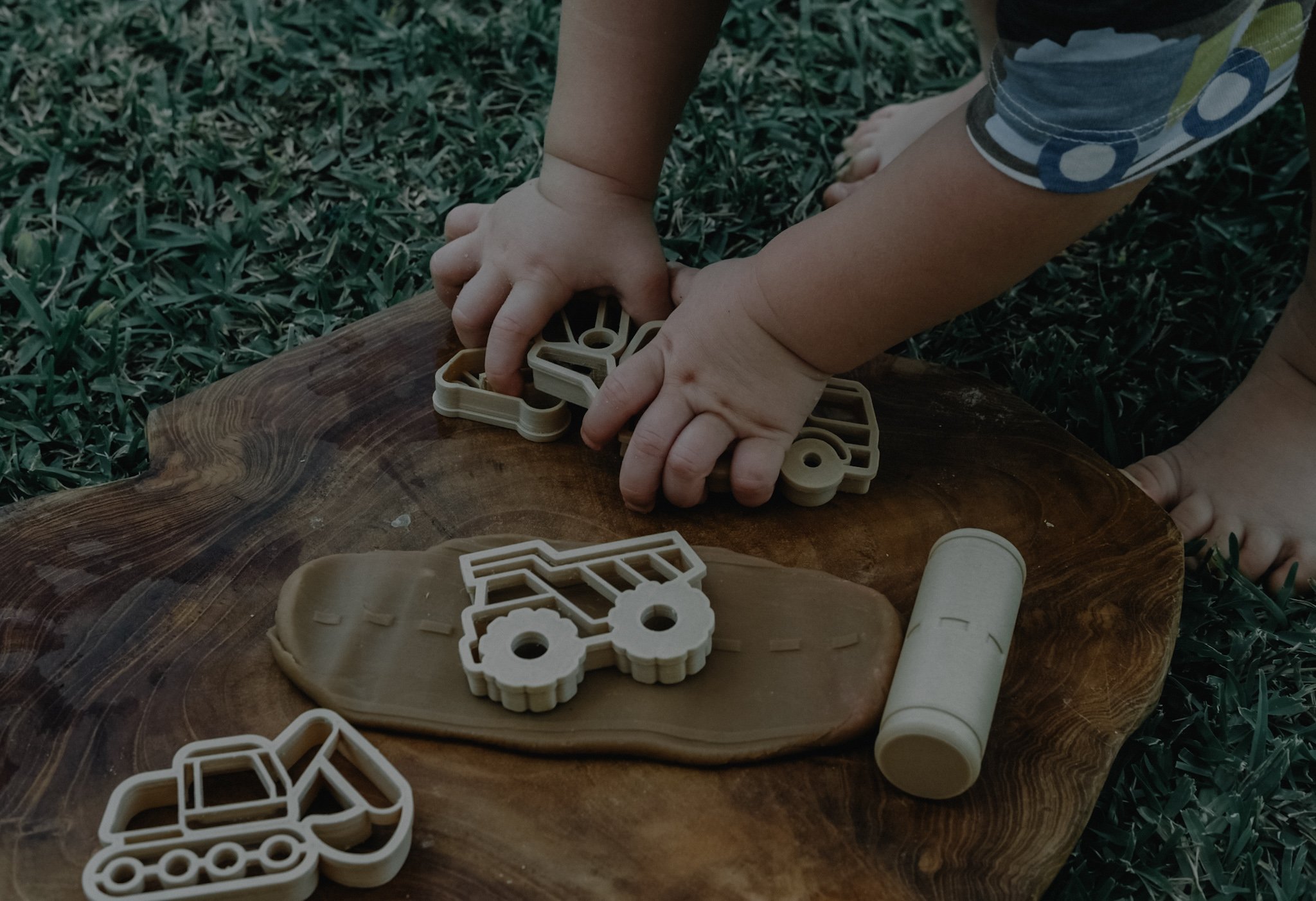 Child playing with construction-themed playdough cutters on natural wood — Australian made sensory play tools.