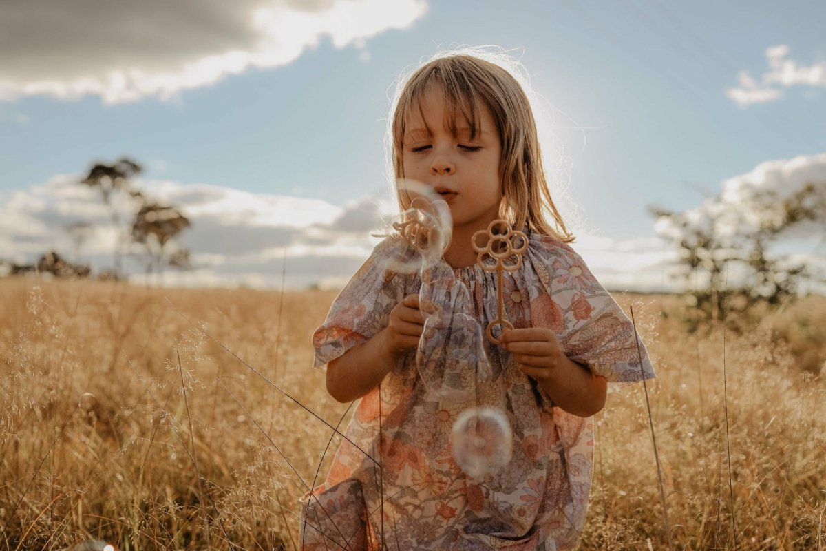 Girl blowing flower bubbles outdoors using a eco-friendly flower bubble wand – Kinfolk Pantry