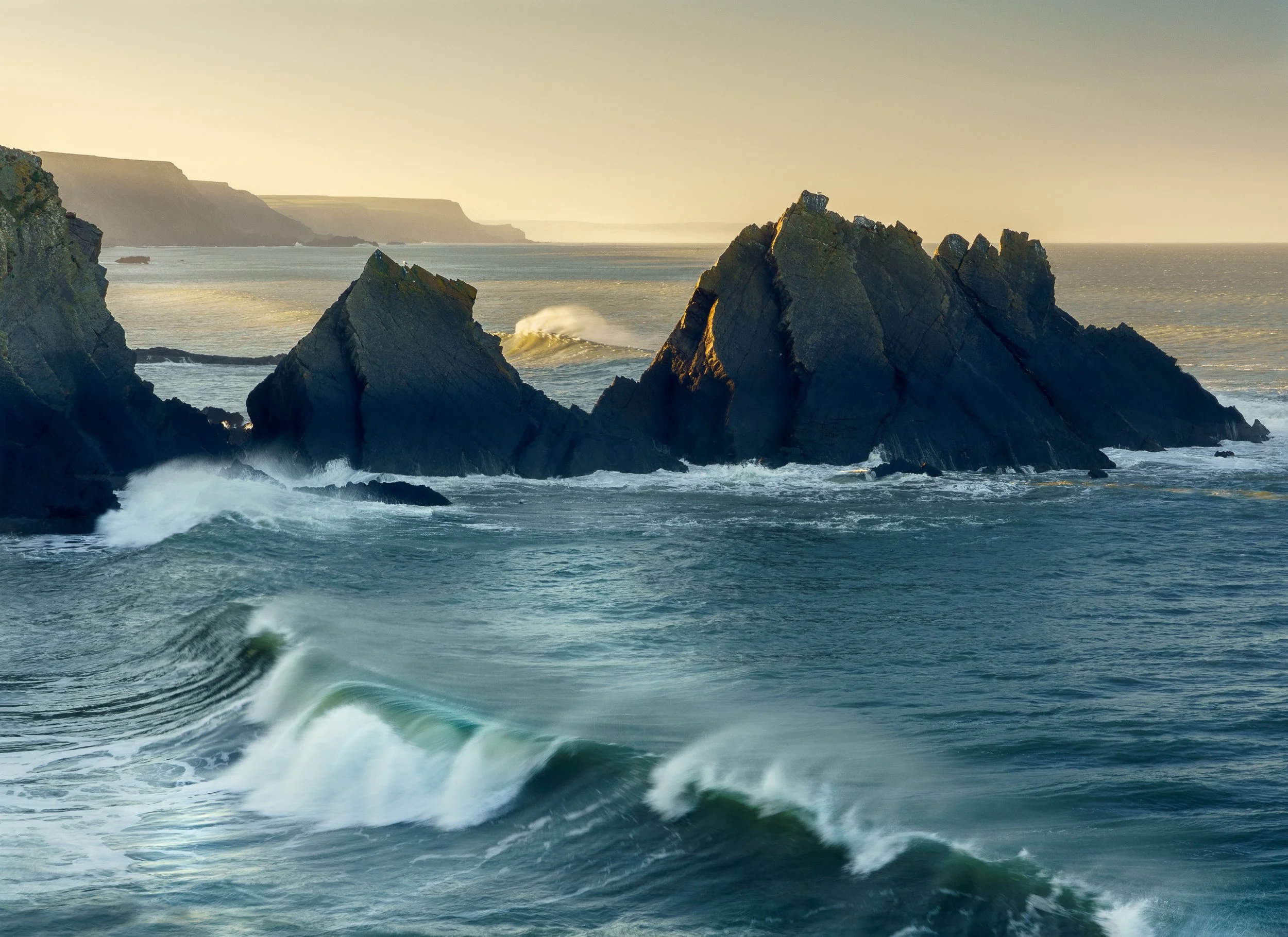 Hartland Point as the sun just pokes crests the land to the left allowing some rays of light across to the sea