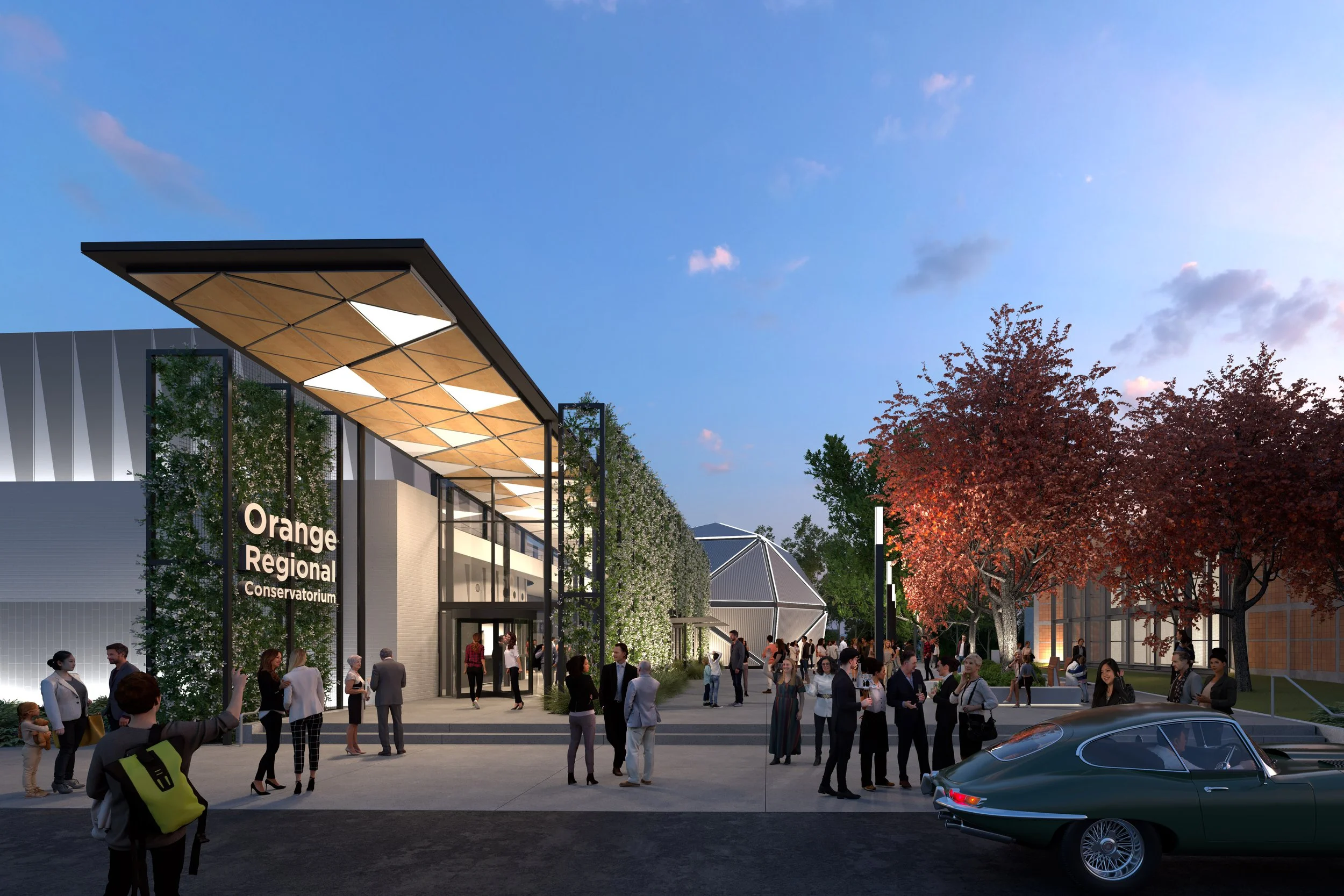A modern outdoor public space with a crowd of people gathered around the entrance of Orange Regional Conservatorium. The building features large glass windows, a distinctive canopy, and greenery on the facade. There are trees with reddish leaves, a clear evening sky, and a parked sports car in the foreground.