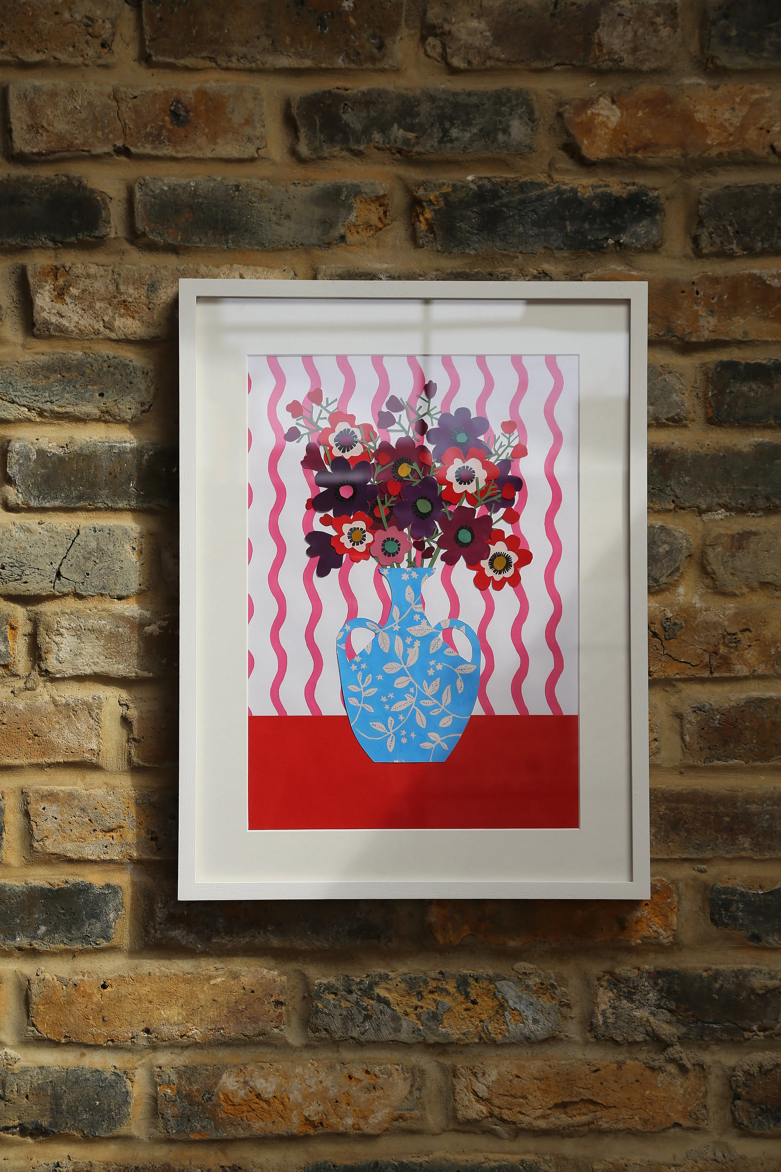 Framed Anemones on brick wall.