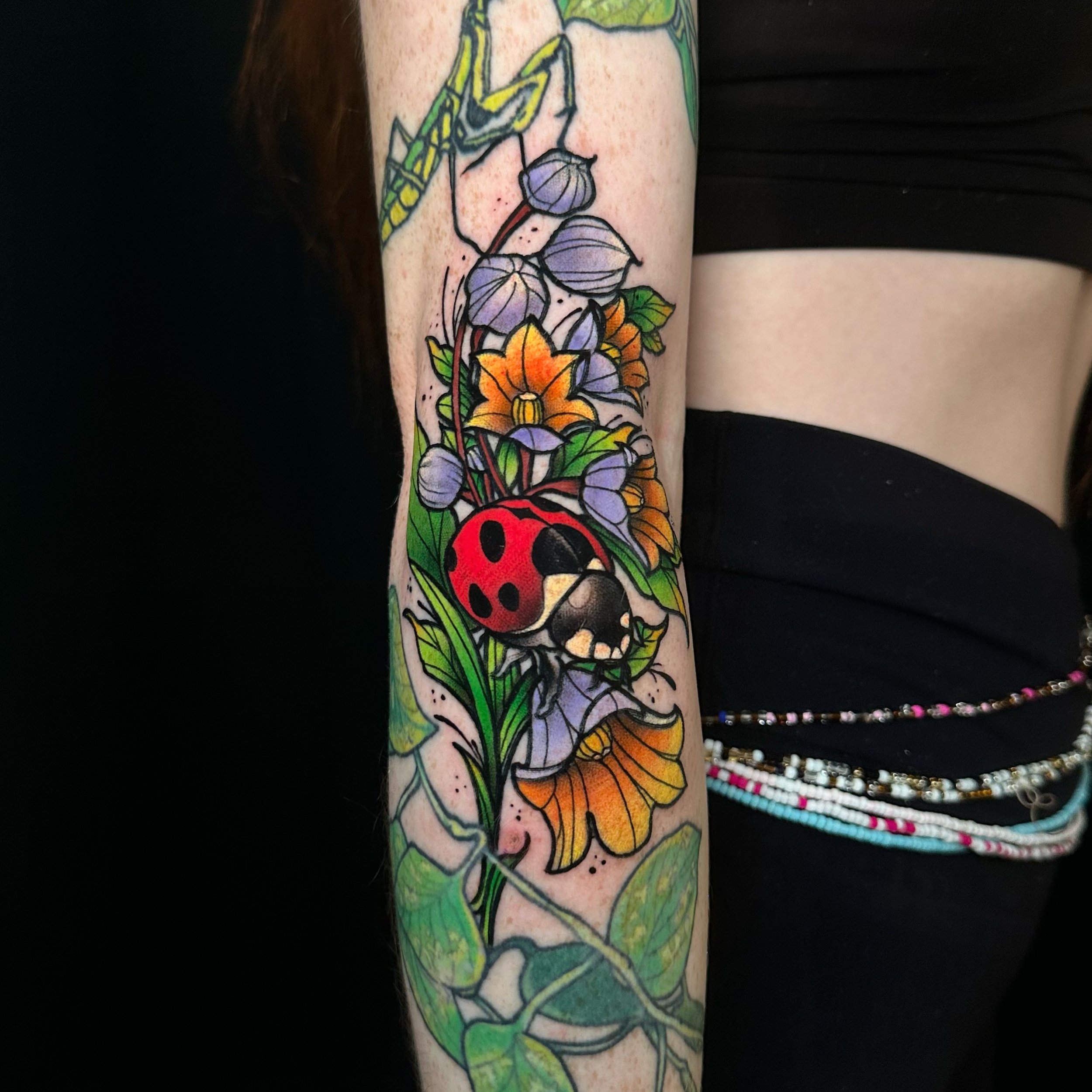 Tattoo ideas arm of a ladybug in nature design in colour tattoo