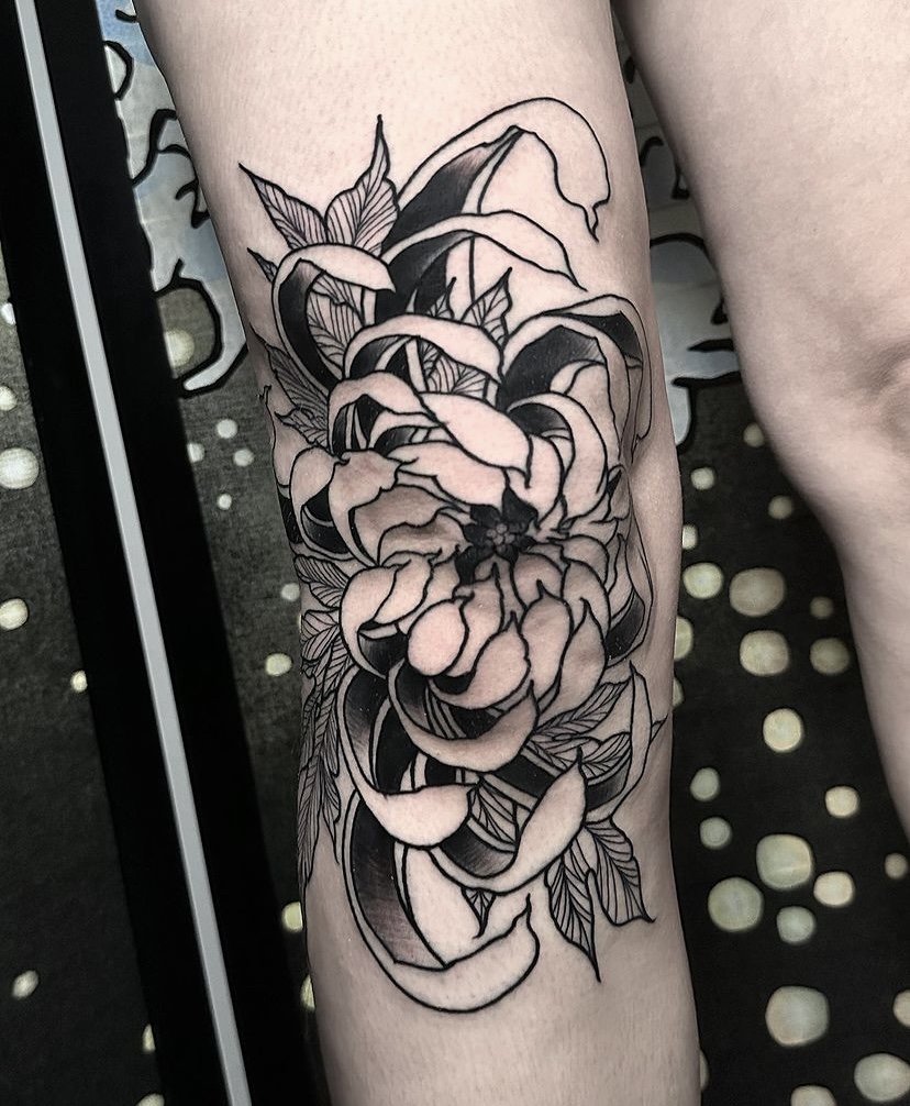 Flower tattoo idea on knee in blackwork tattoo style