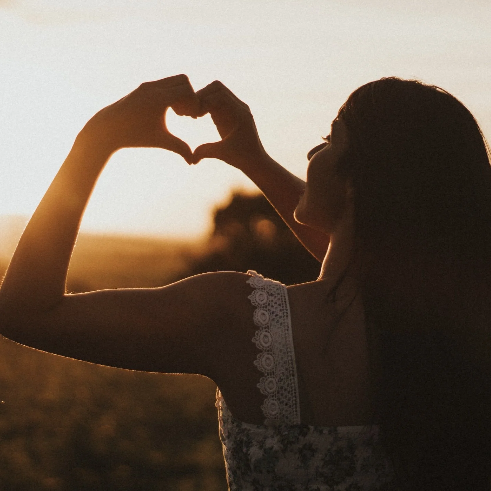 Silhouette of a woman making a heart shape with her hands during sunset. Therapy for Women in Bend, OR - Bend Thoughts & Therapy.