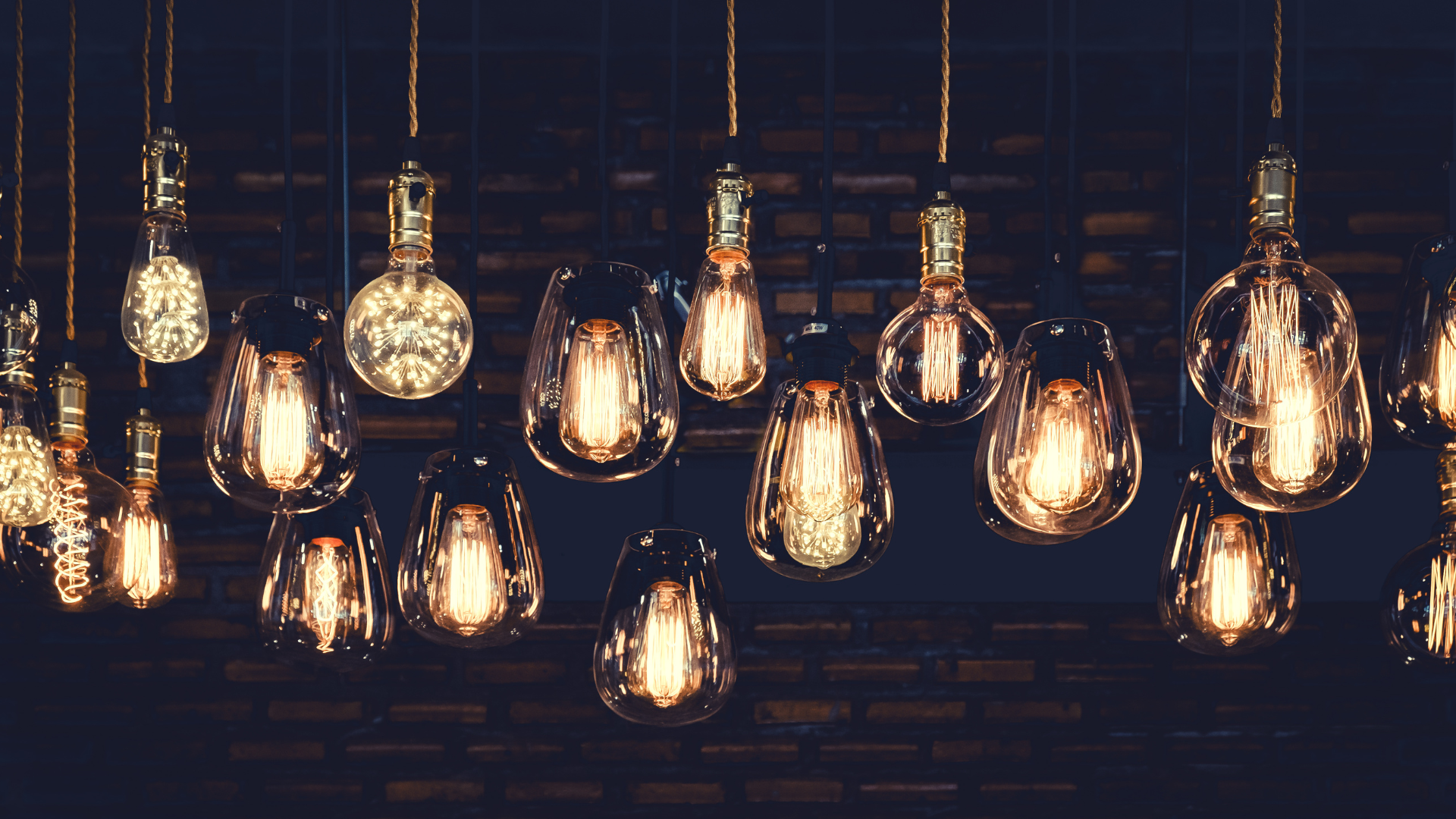 Multiple hanging Edison-style filament light bulbs illuminating against a dark background. Bend Thoughts & Therapy in Bend, OR.