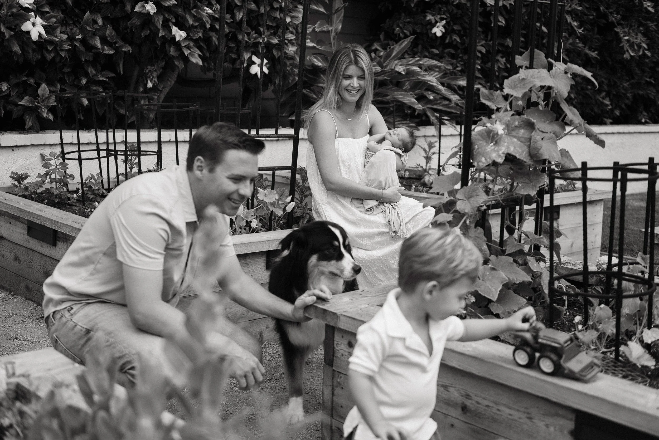 Highly recommended baby photographer in Orange County documents candid family moment in backyard garden,  in home family photos