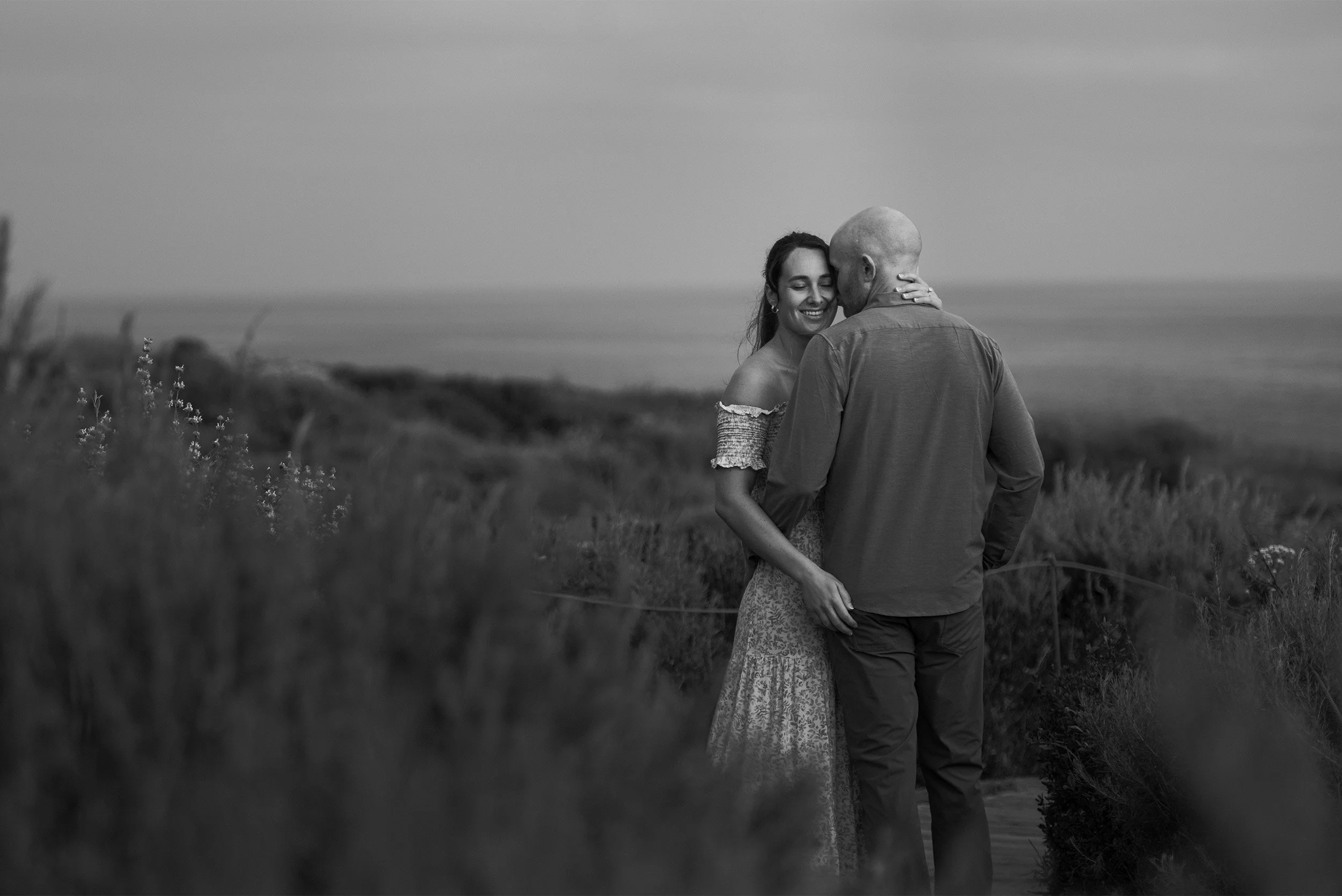 Orange County engagement photographer captures couple embracing along the  Crystal Cove coastline in candid black and white