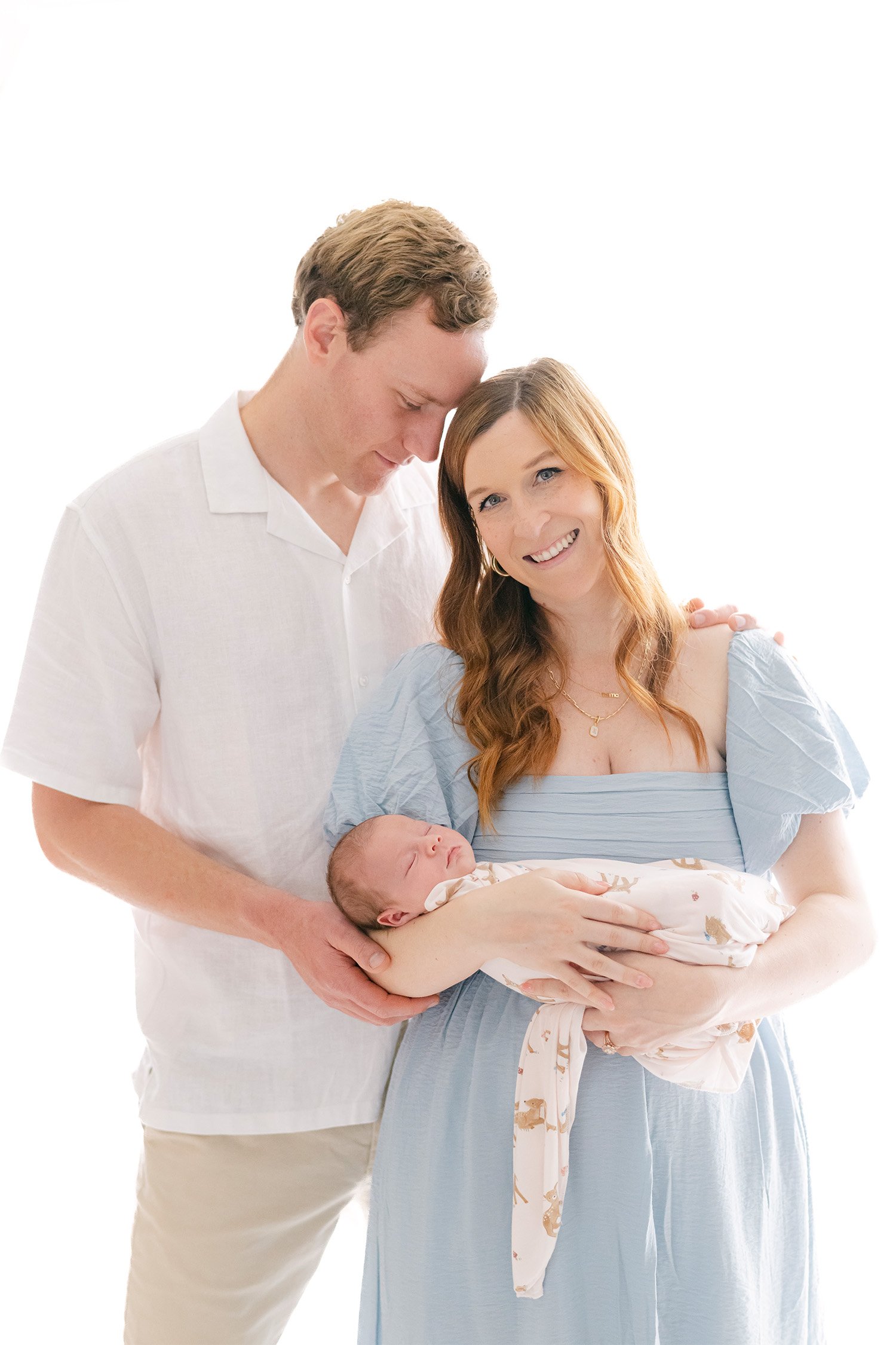 Parents holding sleeping newborn wrapped in swaddle, award-winning baby photographer in Orange County
