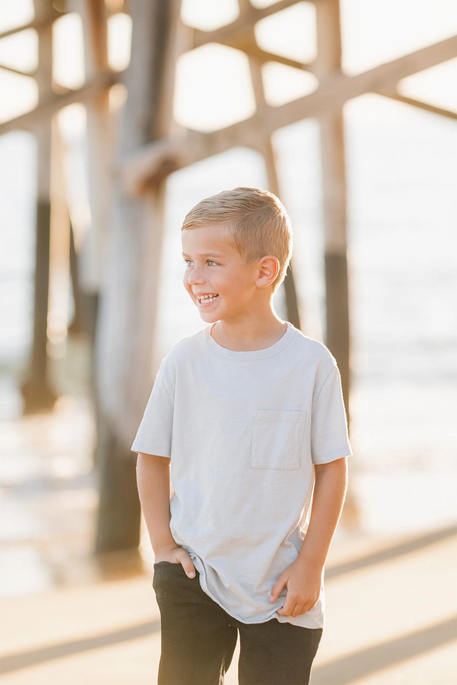 Award-winning family photographer captures candid portrait of a smiling boy under the Newport Pier