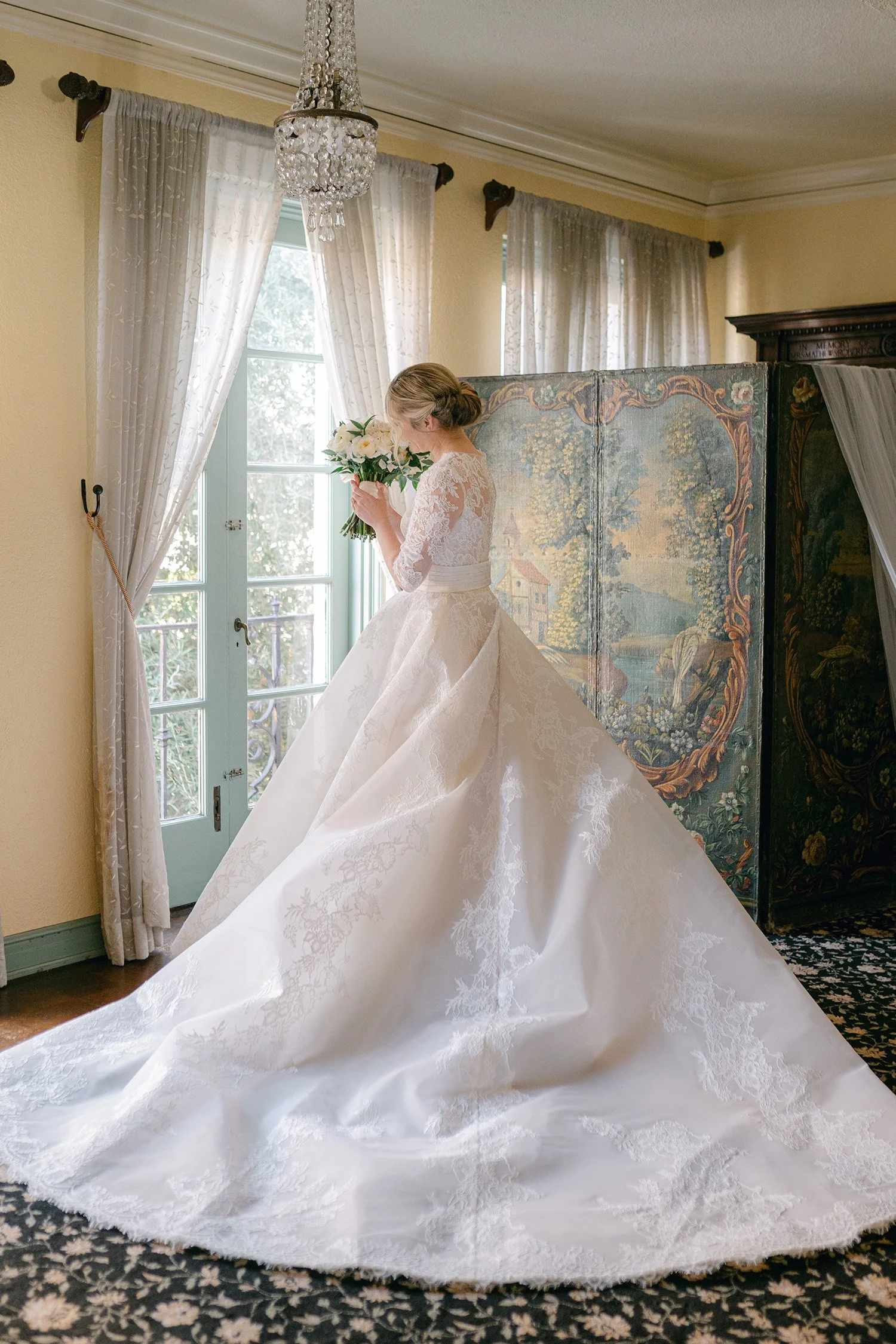 Orange County wedding photographer captures bride in lace ball gown beside antique tapestry screen in the historic Ebell of Los Angeles