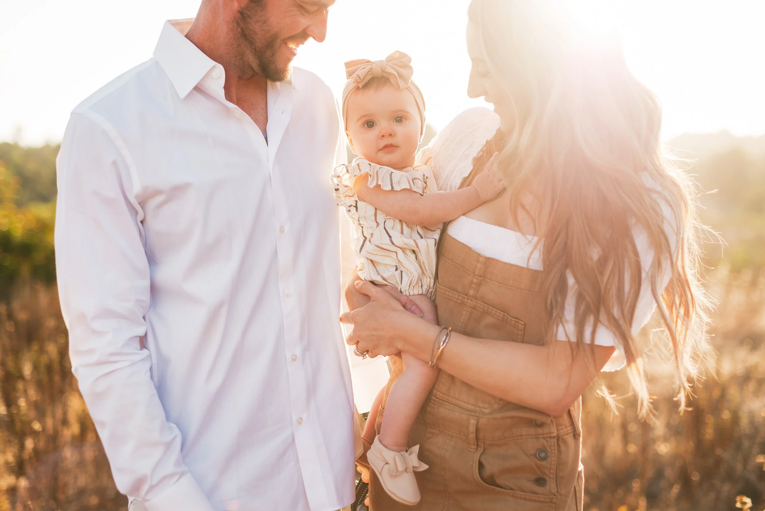 Orange County family photographer captures close-up golden hour portrait of parents holding baby girl