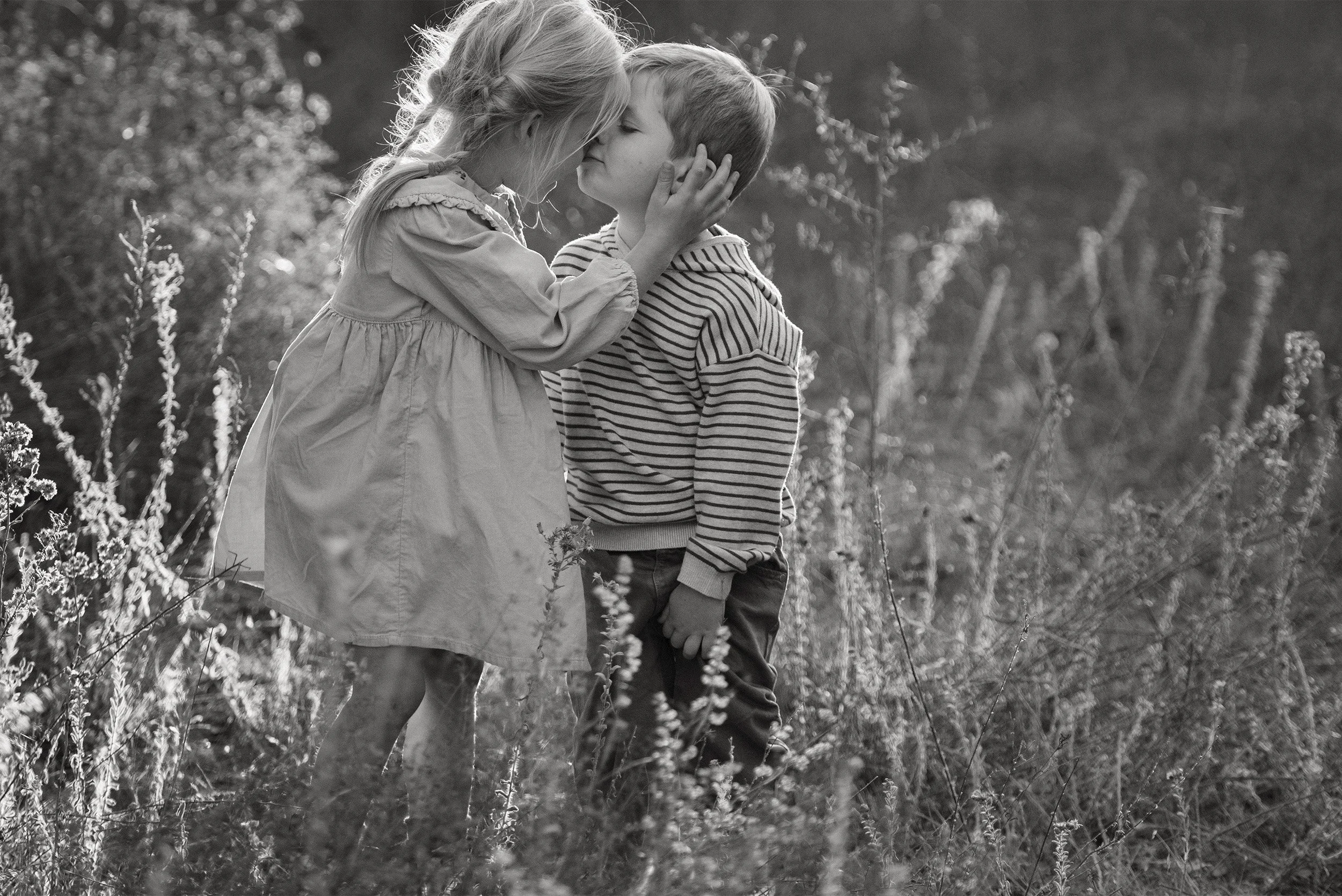 Sibling portrait photography in black and white featuring children in tall grass field, Orange County family photographer