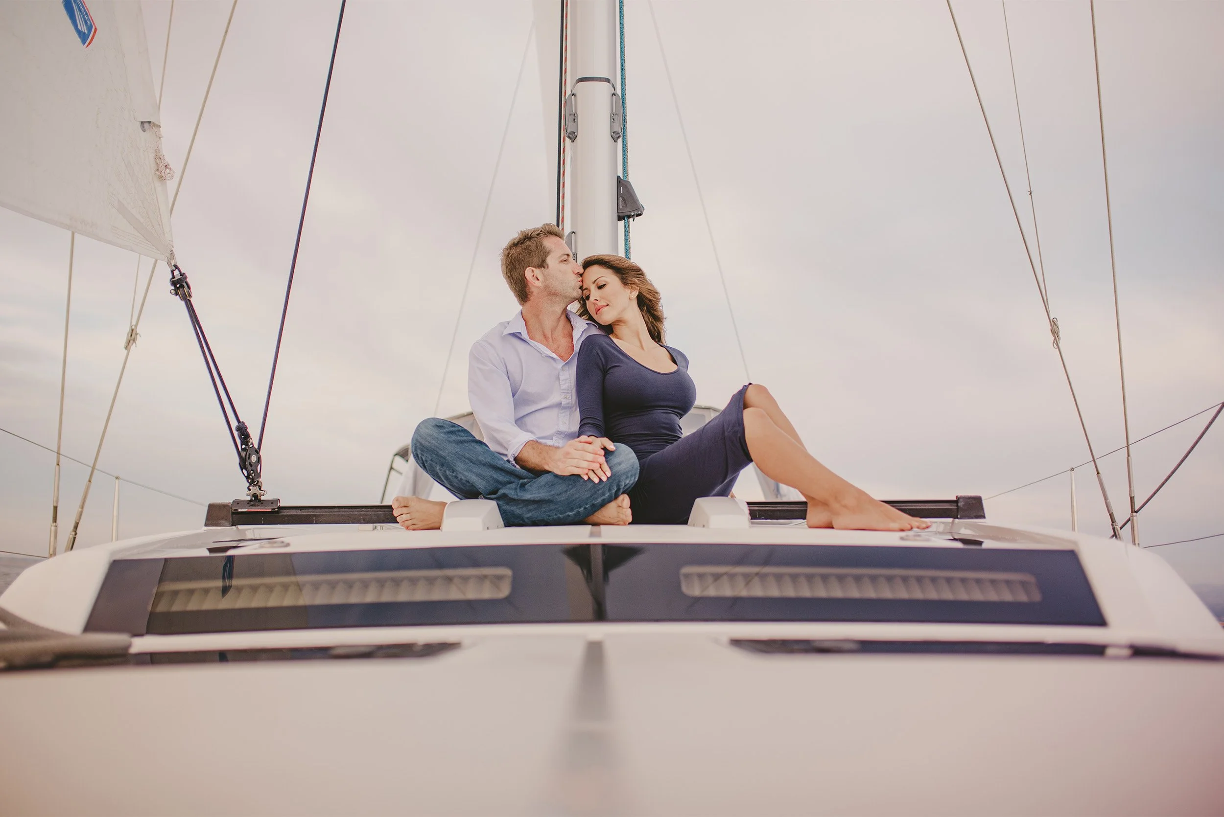 Couple kissing on the bow of a sailboat, Newport Beach yacht engagement photos