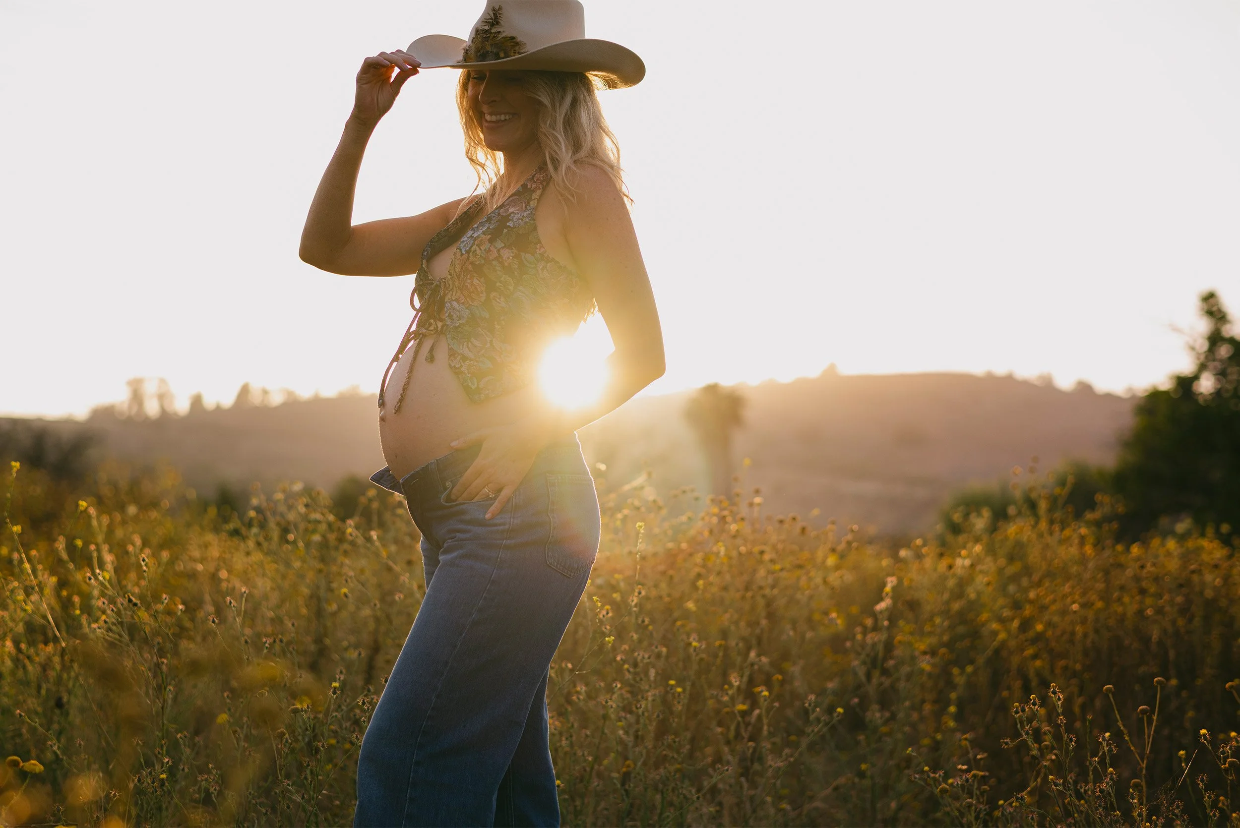 Orange County maternity photographer captures glowing sunset portrait of expecting mother in wildflower field
