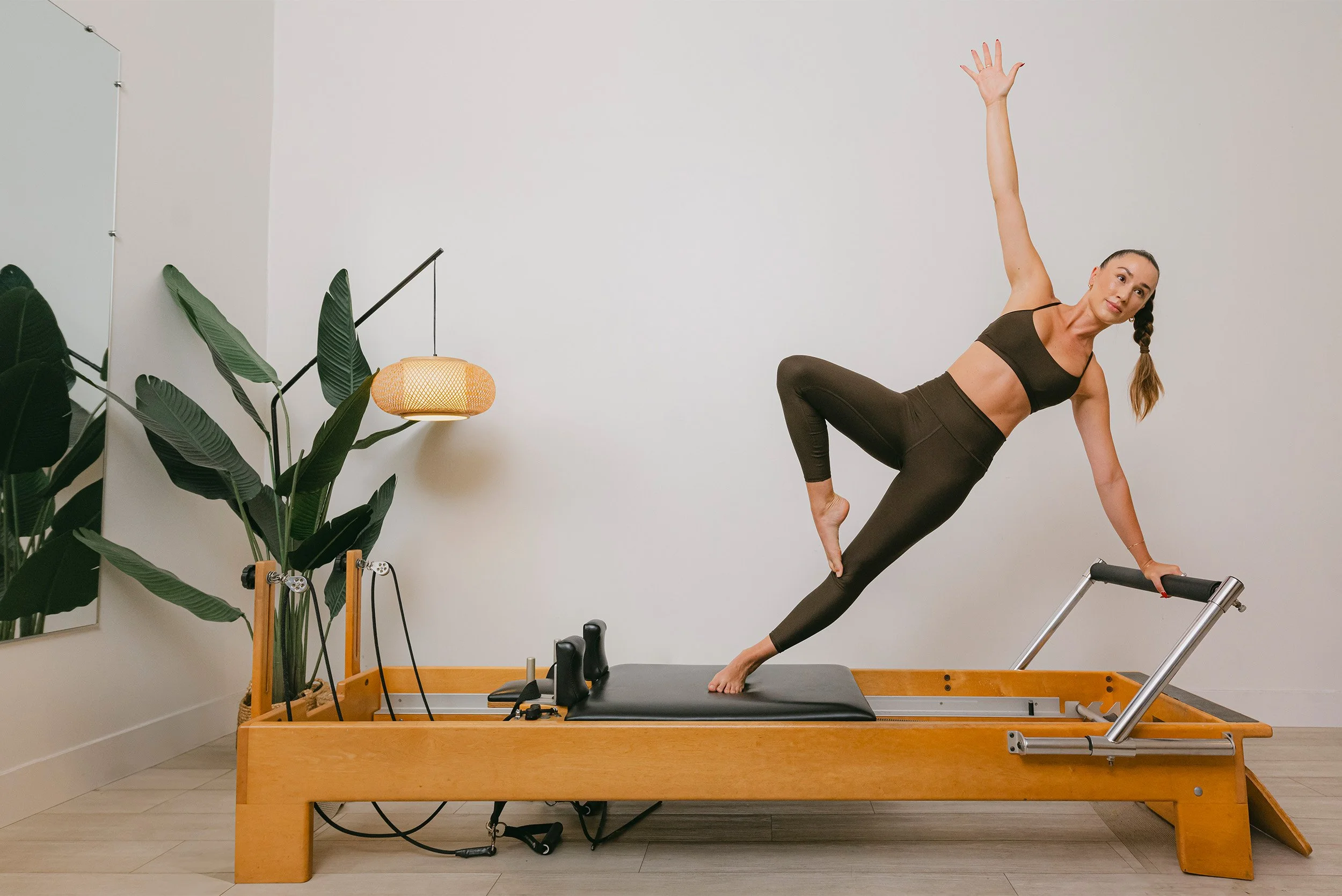 Fitness brand photography of instructor demonstrating side plank on Pilates reformer machine, Orange County brand photographer