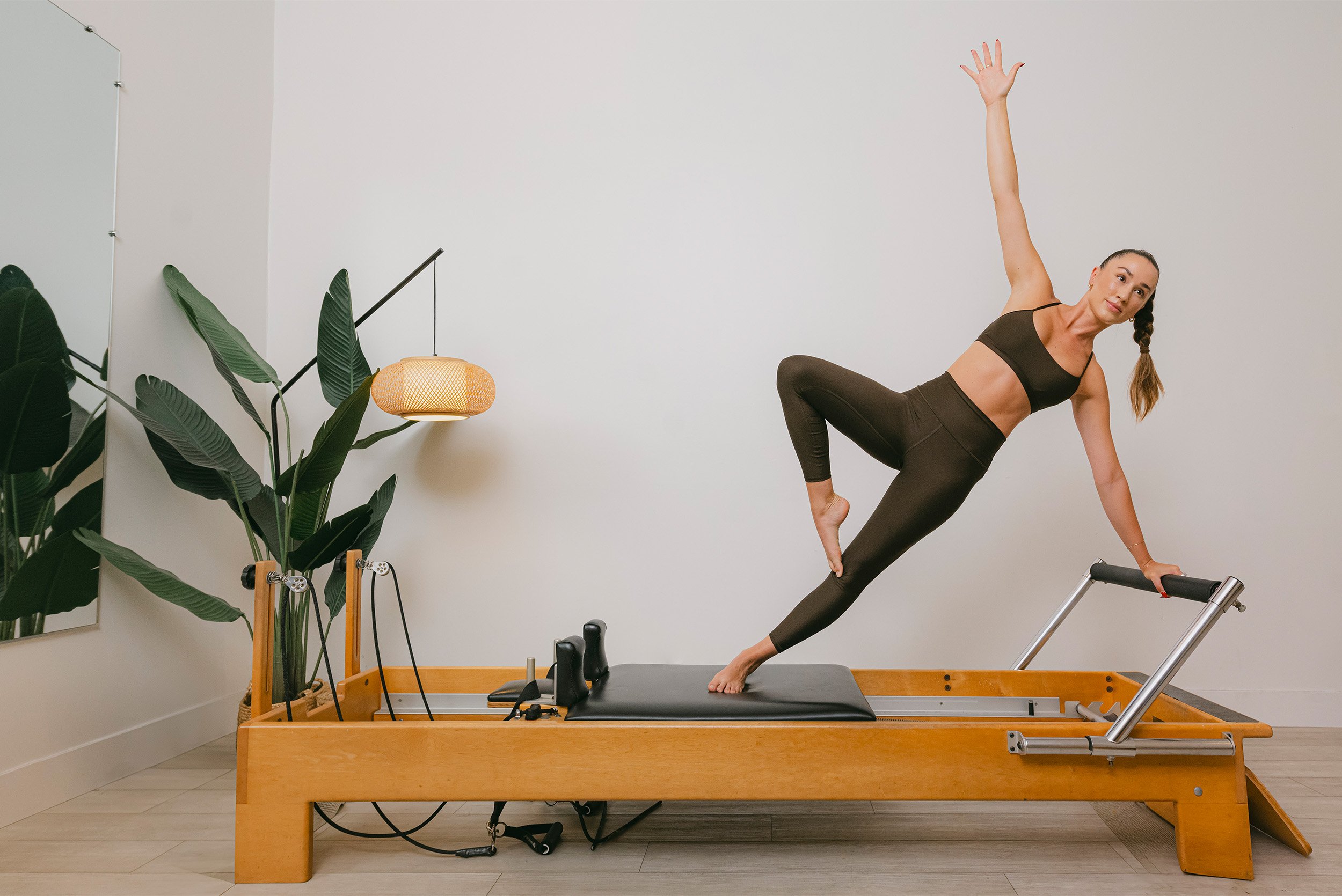 Fitness brand photography of instructor demonstrating side plank on Pilates reformer machine, Orange County brand photographer