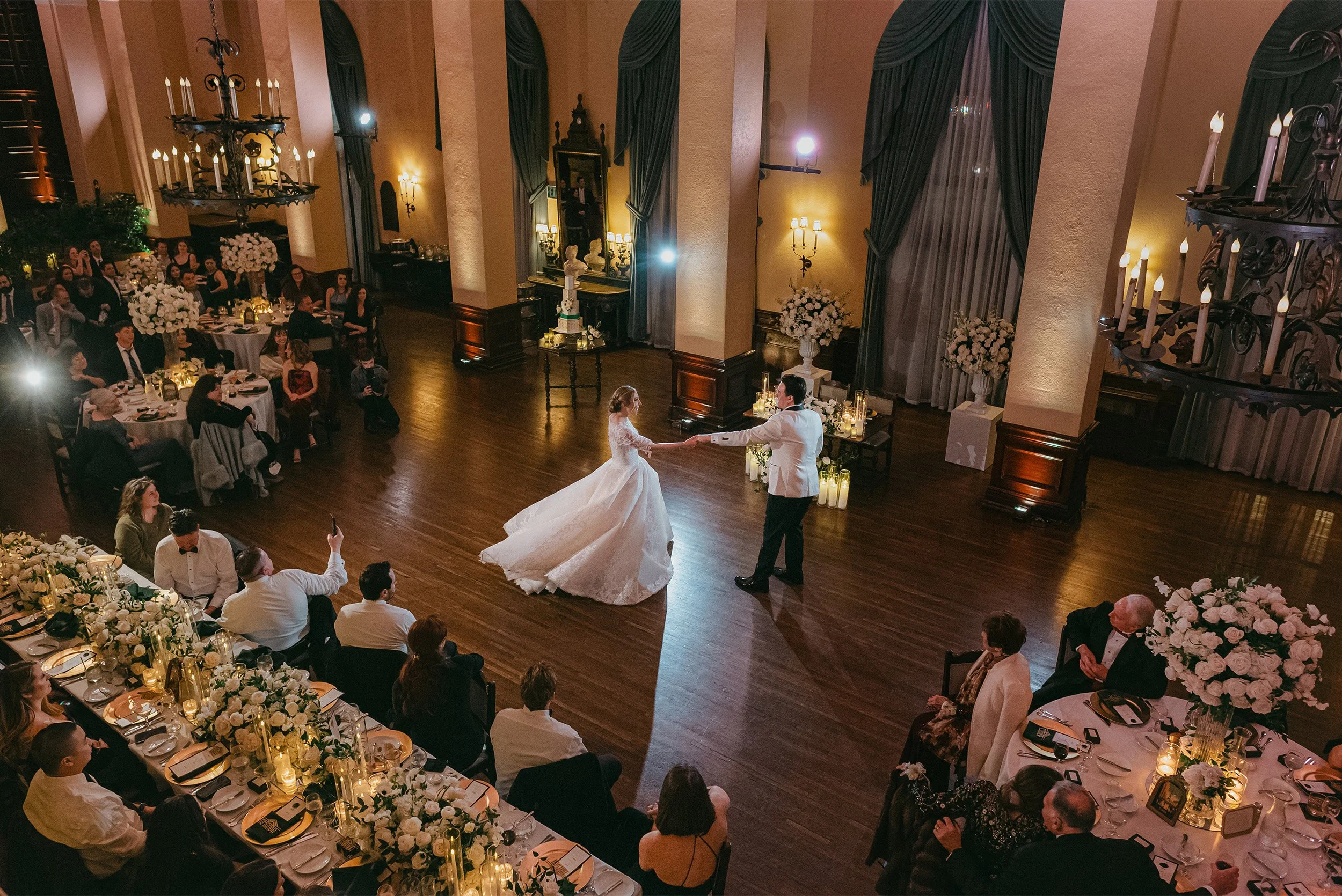 Bride and groom sharing first dance in elegant ballroom reception at The Ebell of Los Angeles with candlelit tables, Los Angeles Wedding
