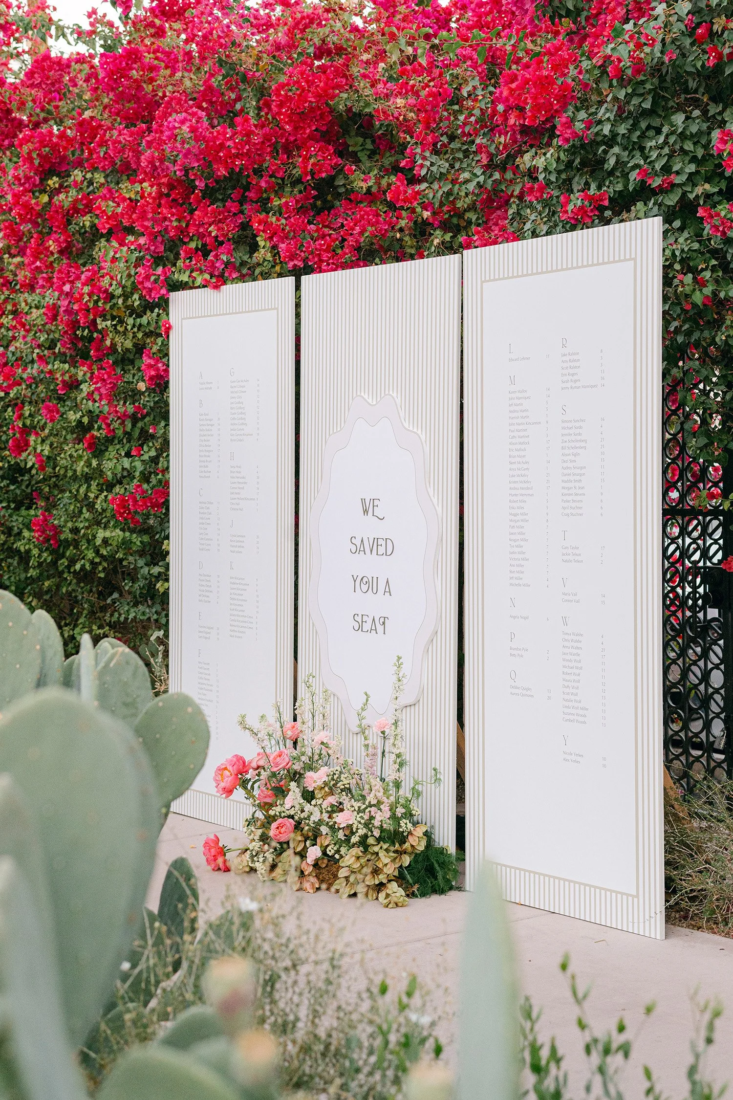 Award-winning wedding photographer in Orange County captures seating chart framed by vibrant pink bougainvillea and desert cacti, Casa Cody in Palm Springs wedding venue