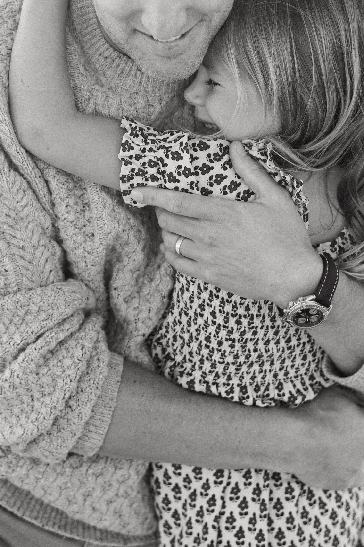 Black and white close-up of father embracing his young daughter in a floral dress, Family photography session in Orange County