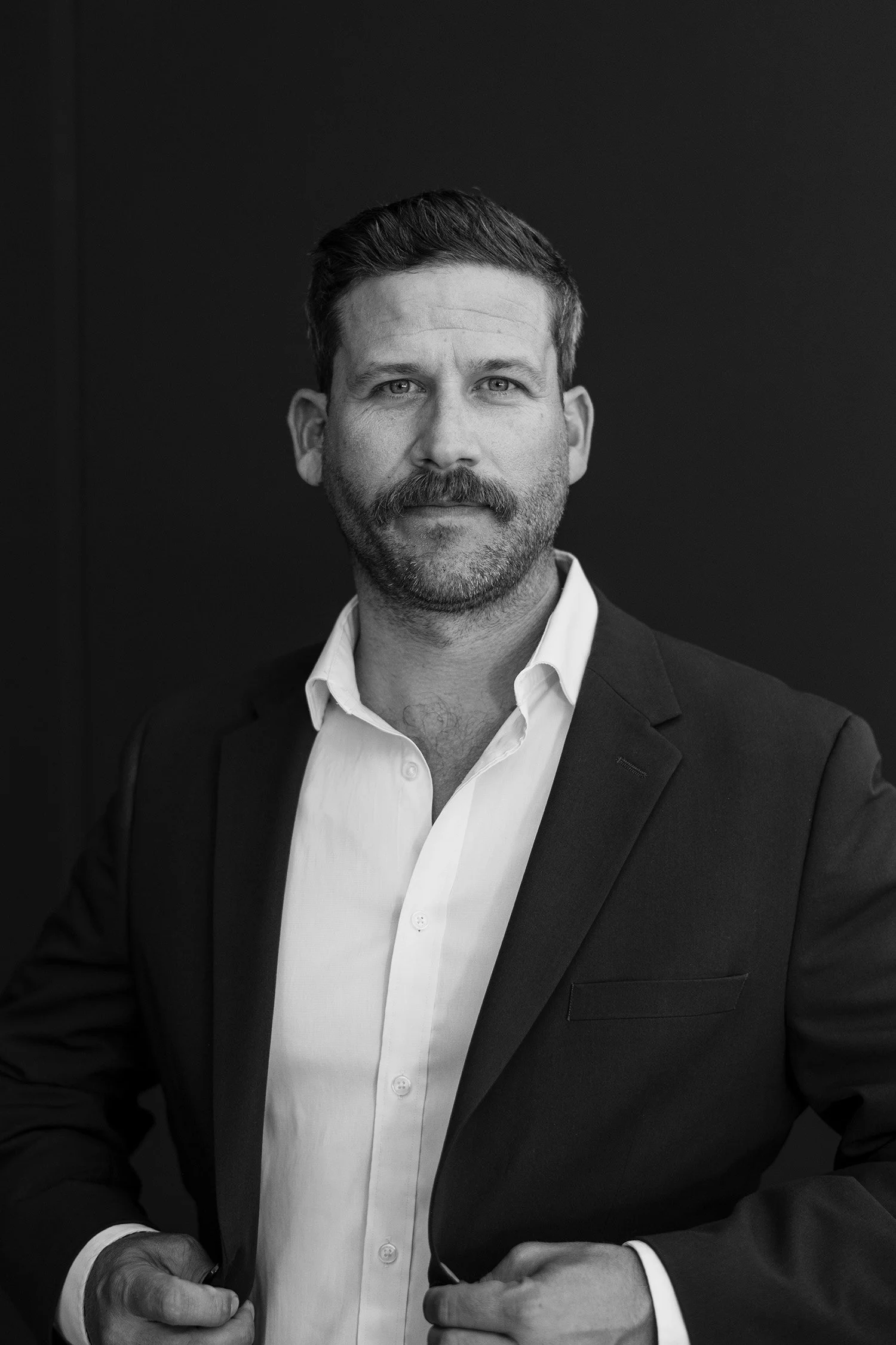 Award-winning corporate photographer captures dramatic black-and-white executive headshot against dark backdrop
