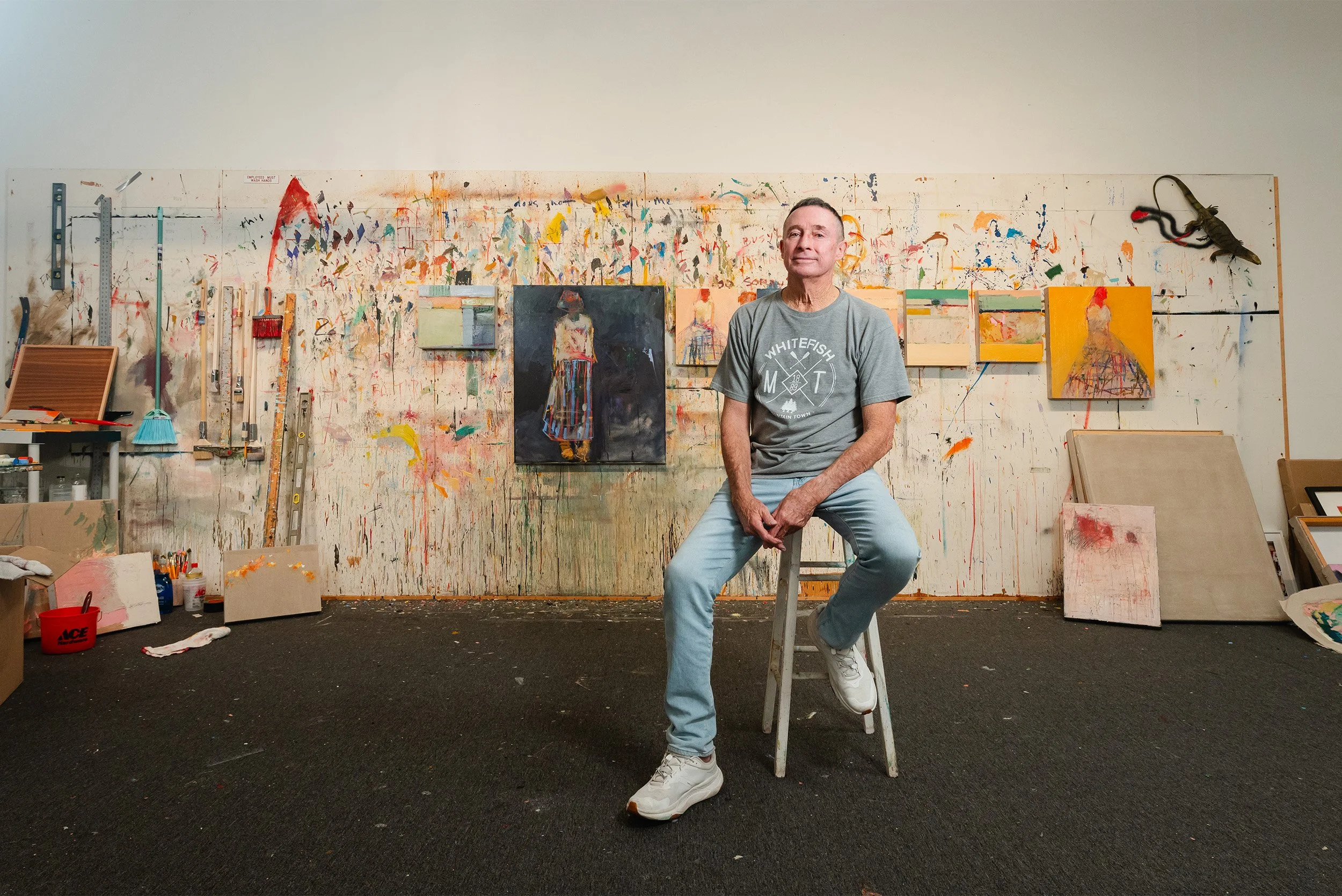 Highly recommended portrait photographer captures artist portrait in working studio with painted backdrop wall