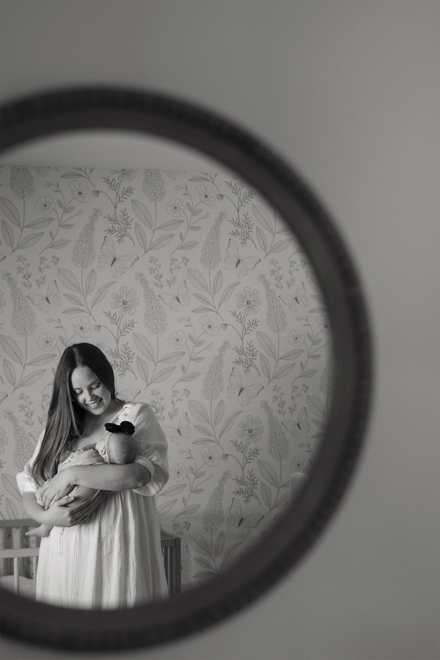 Black and white mirror reflection of mother holding newborn in nursery, Orange County newborn photographer