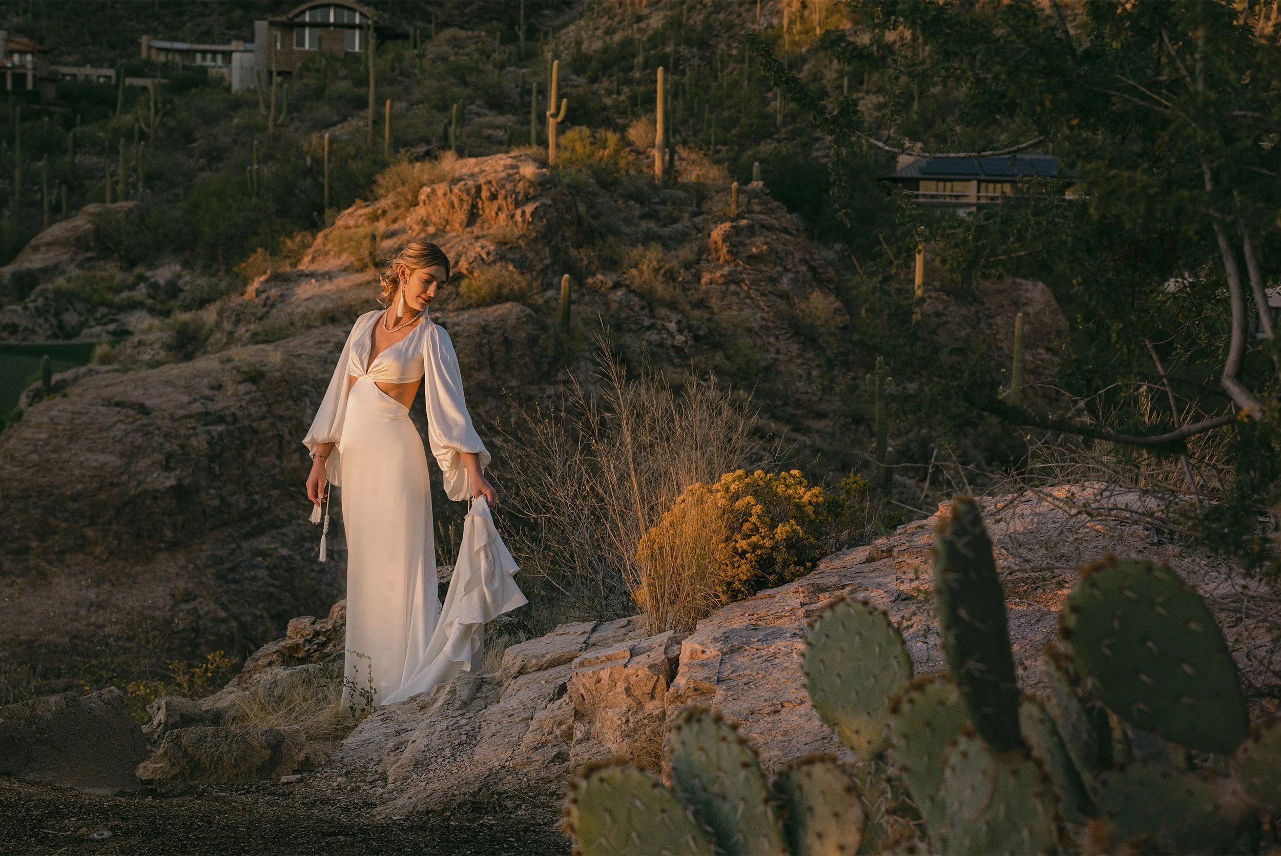 Award-winning wedding photographer in Orange County captures bride in flowing white gown among desert cacti and golden hour light
