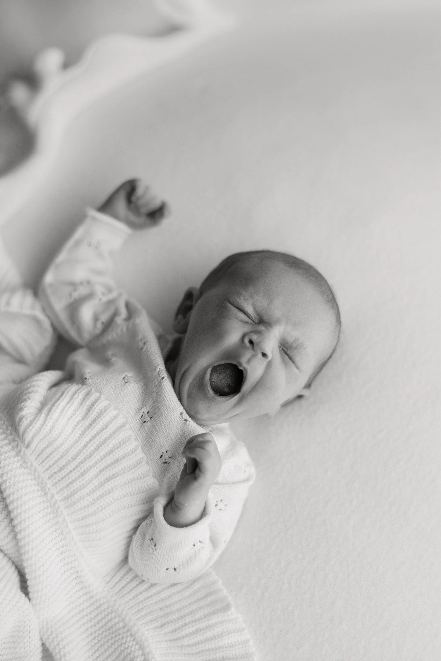 Black and white photo of yawning newborn stretching arm, Orange County baby photographer