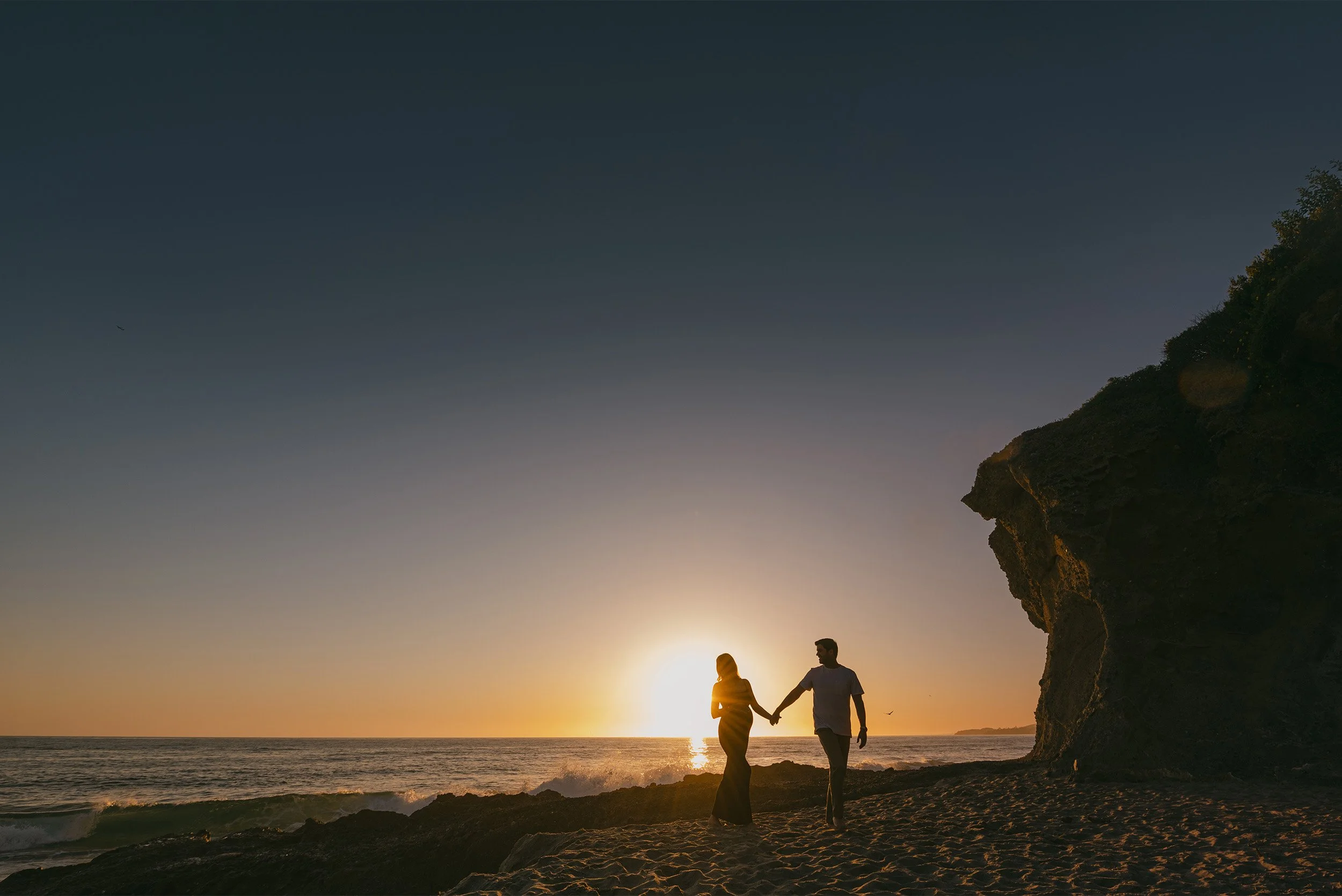 Silhouette of couple holding hands in Laguna Beach at sunset, highly recommended maternity photographer Laguna Beach