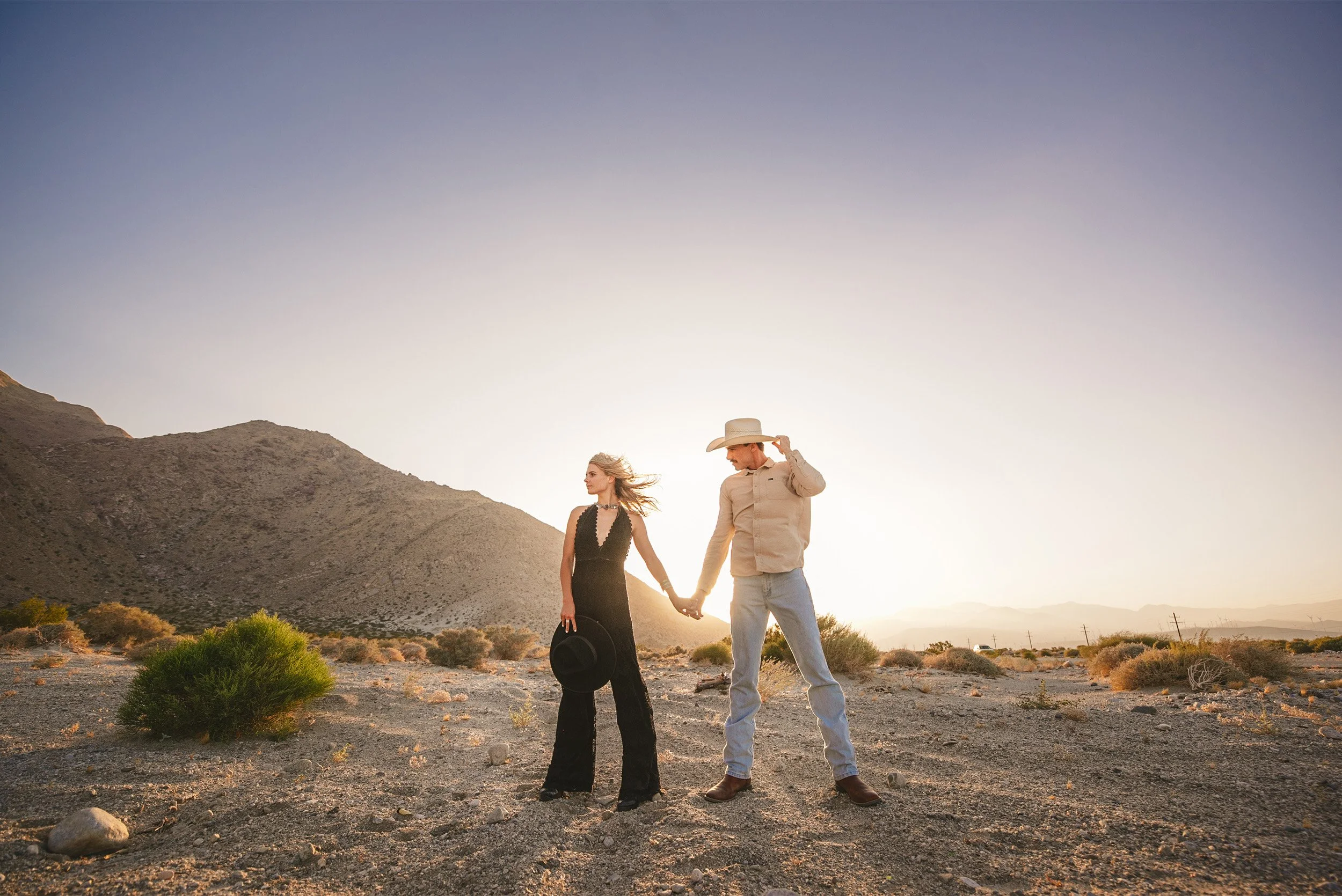 Couple holding hands walking through the desert at sunset, Palm Springs engagement photo session