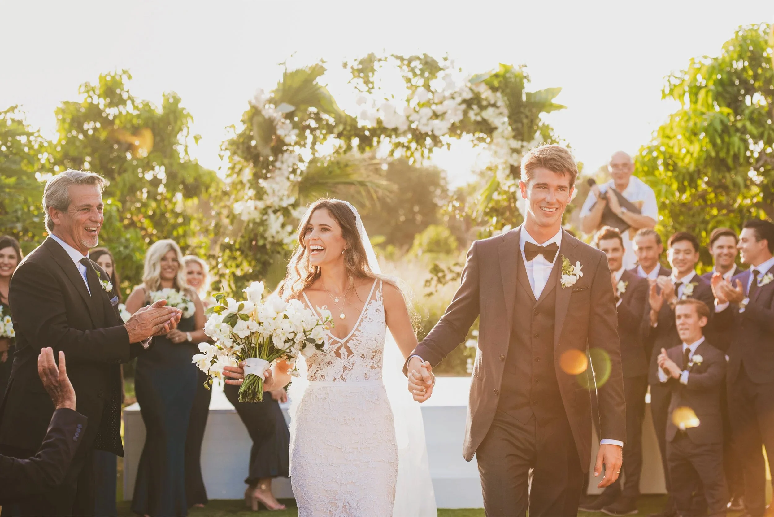 Bride and groom walking down the aisle as guests applaud, Cabo sunset garden wedding ceremony