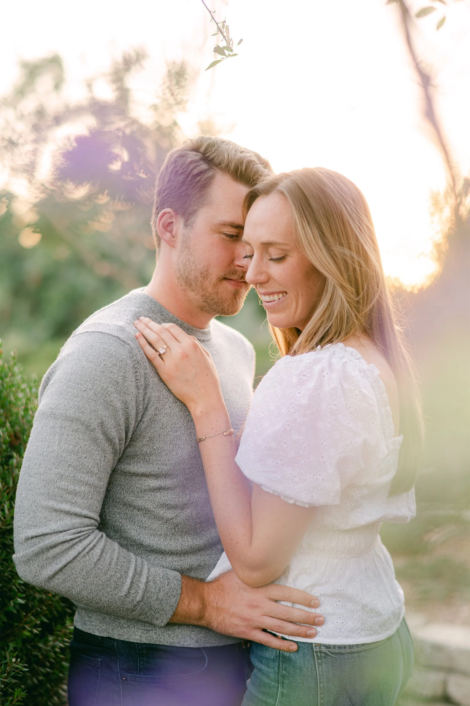 Orange County engagement photographer captures couple embracing in golden hour sunlight with warm sun flare