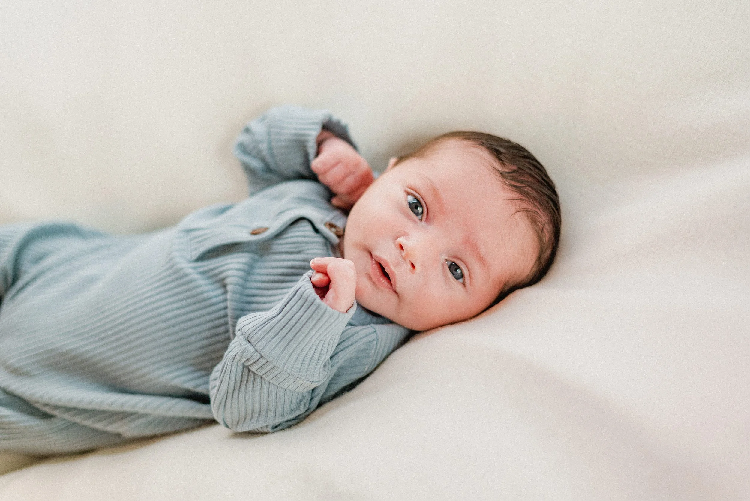 Orange County newborn photographer captures close-up portrait of alert baby boy in blue ribbed outfit