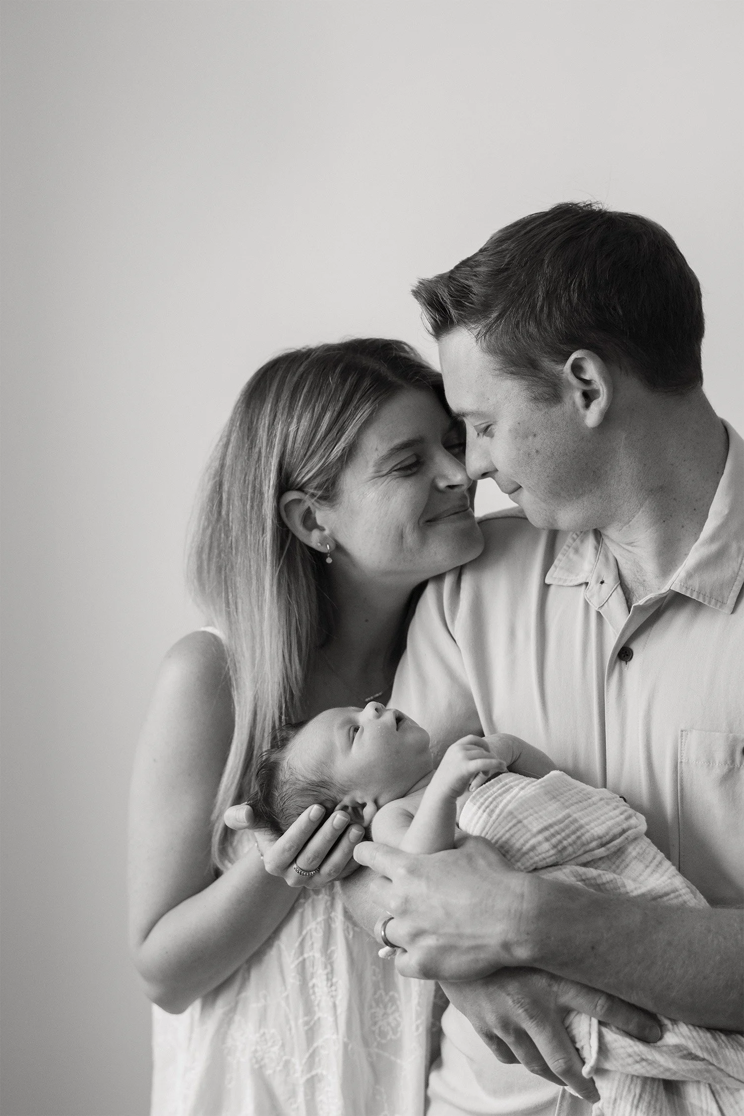 Black and white close-up of parents smiling at newborn in arms, Orange County newborn photographer