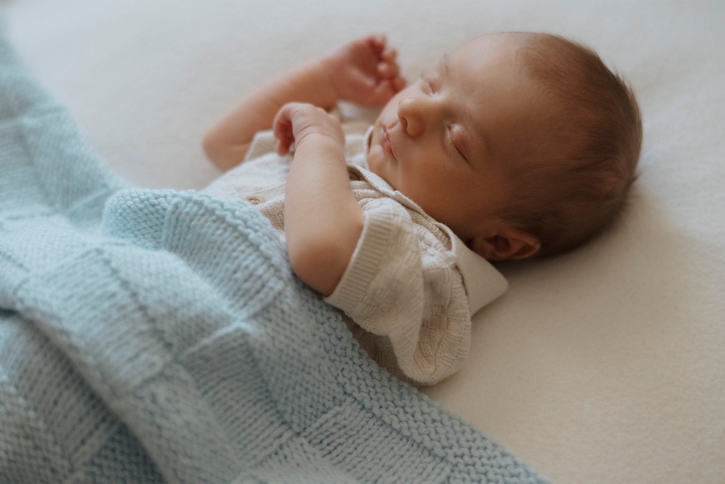 Award-winning newborn photographer in Orange County photographs sleeping baby in cream knit sweater, in home newborn photos